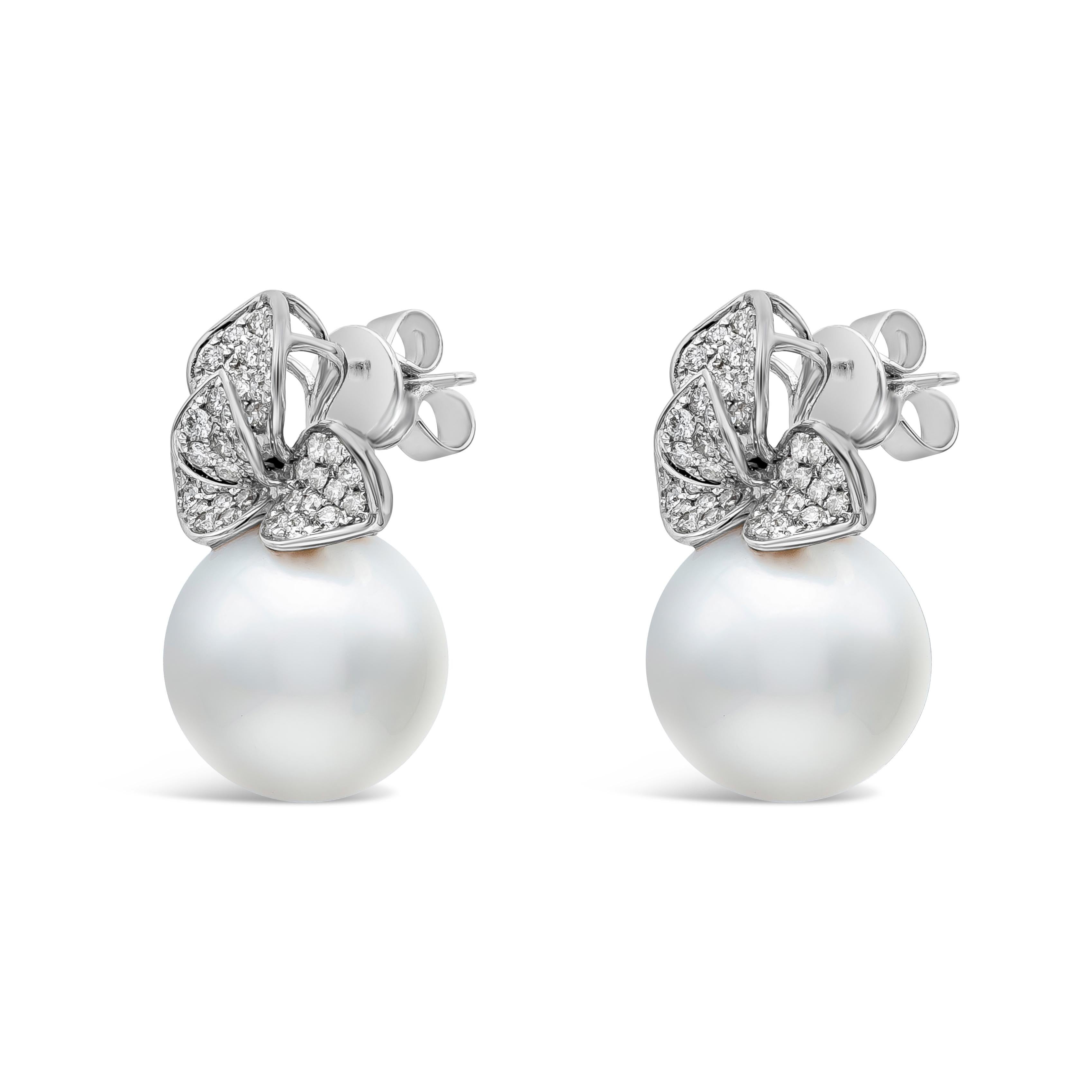 This beautiful earrings are showcasing 13-14 mm south sea pearls. Earrings consist of 96 round cut diamonds weighing 0.98 carats total, suspended on a diamond encrusted flower design made in 18K White Gold.

Style available in different price