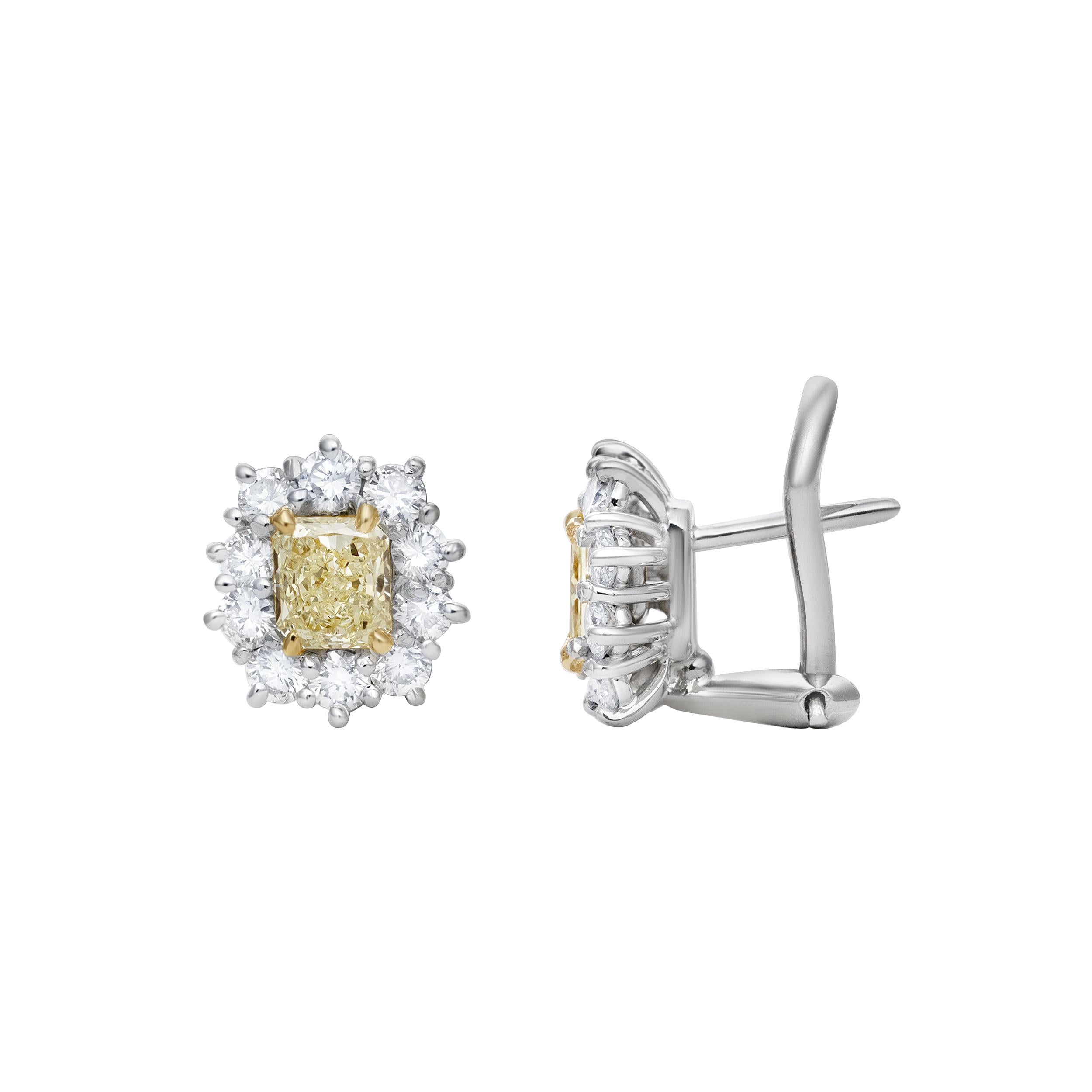 Une belle paire de boucles d'oreilles, mettant en valeur deux diamants jaunes de taille radieuse pesant 1,02 carats au total, de couleur FLY et de pureté VS+, montés sur une monture à quatre griffes en or jaune 18 carats. Accentuée par un halo de