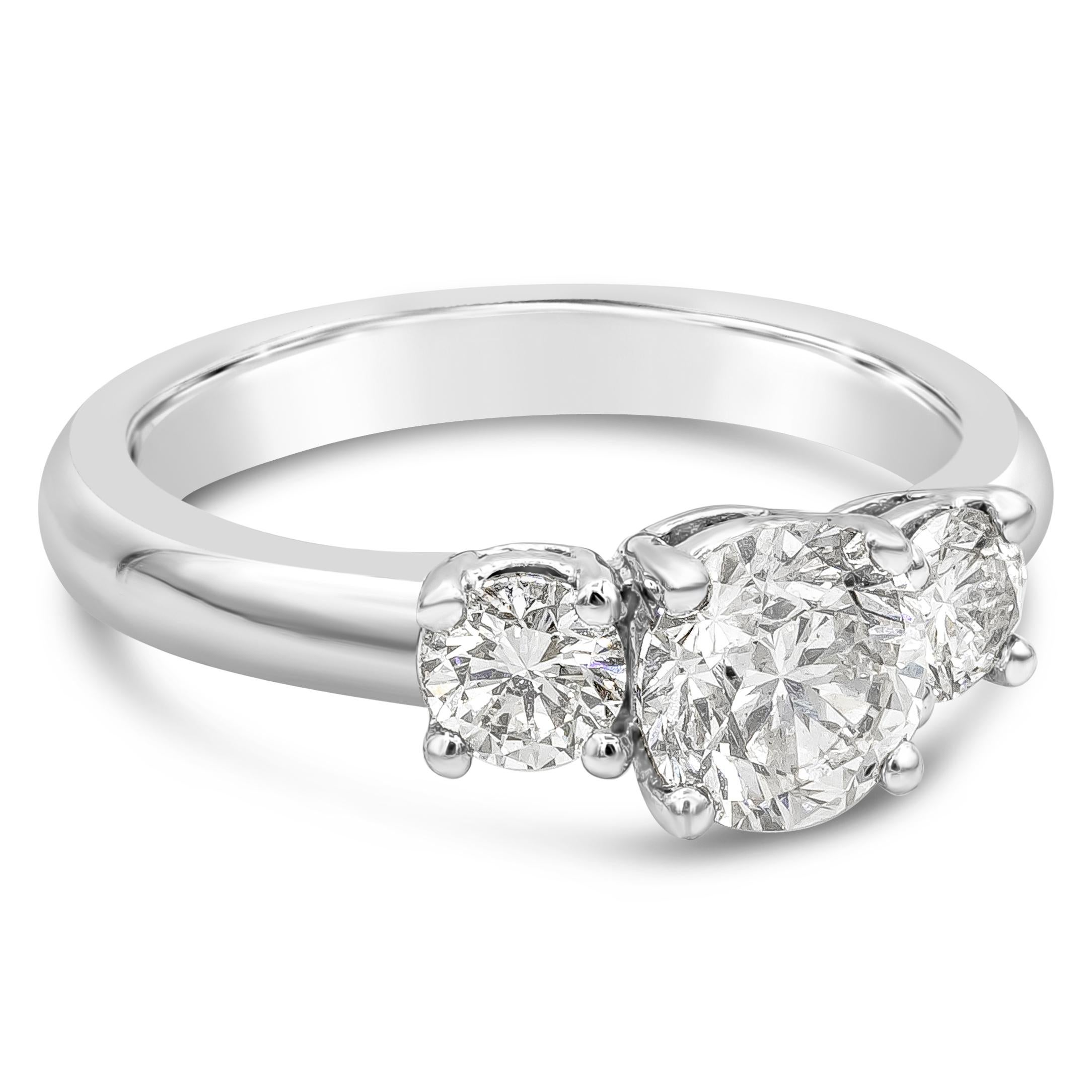 This classy and simple three stone engagement ring showcases a brilliant round diamond center stone weighing 1.03 carats, I color and SI1 in clarity, set in a four prong basket setting. Flanked by two round brilliant diamonds on each side weighing