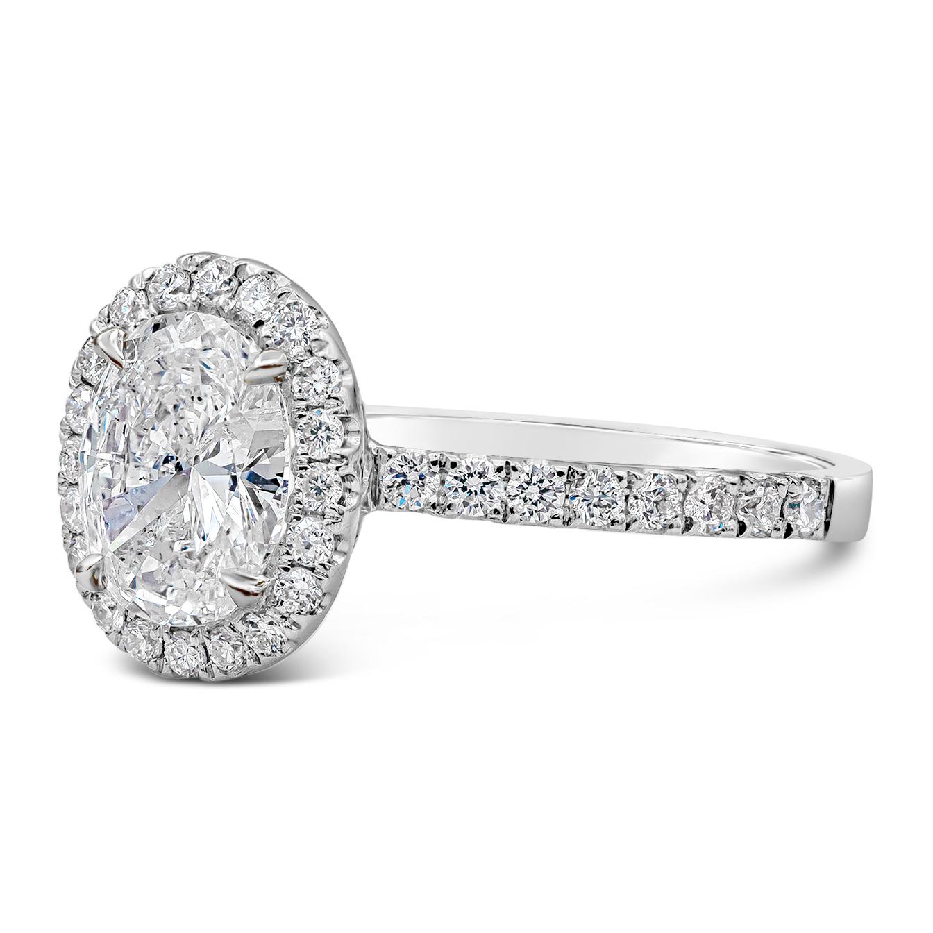 A timeless engagement ring style showcasing a 1.05 carat oval cut diamond surrounded by a single row of round brilliant diamonds. Set in an accented diamond band made in 18k white gold. Accent diamonds weigh 0.44 carats total. Center diamond is D