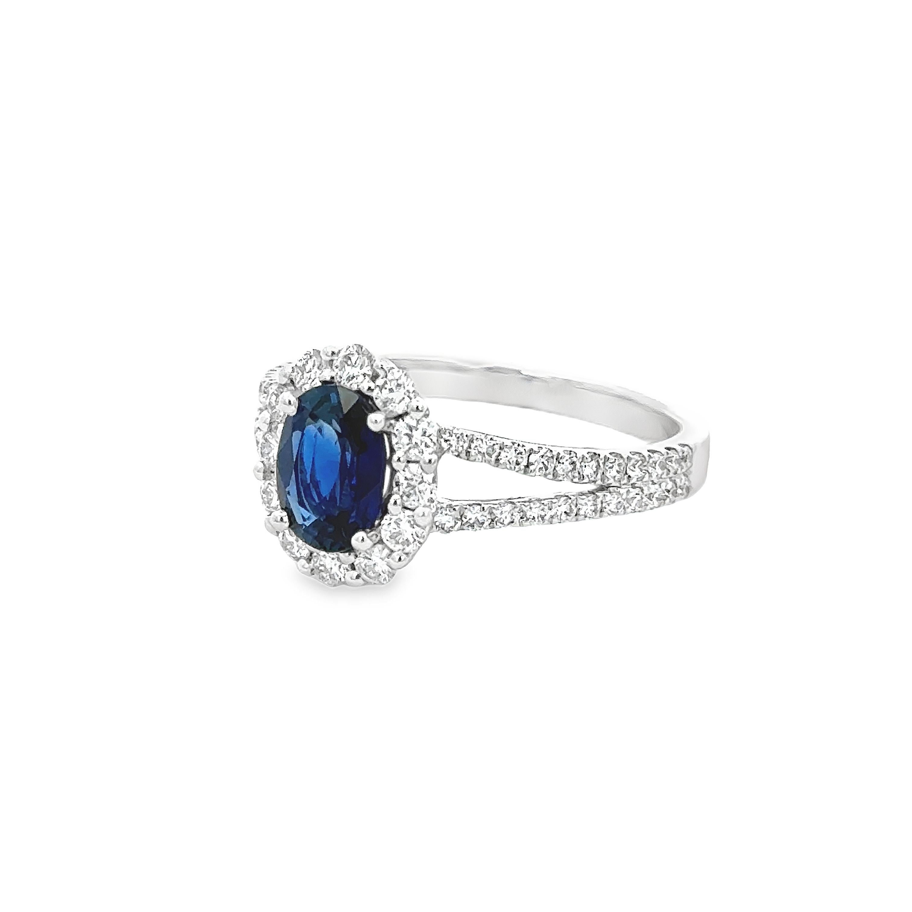 A gorgeous engagement ring, featuring a vibrant 1.08 carats oval cut sapphire, set on a classic four prong setting. Surrounded by a halo of round brilliant cut diamonds and accented by a diamond encrusted split-shank in a half-eternity design.