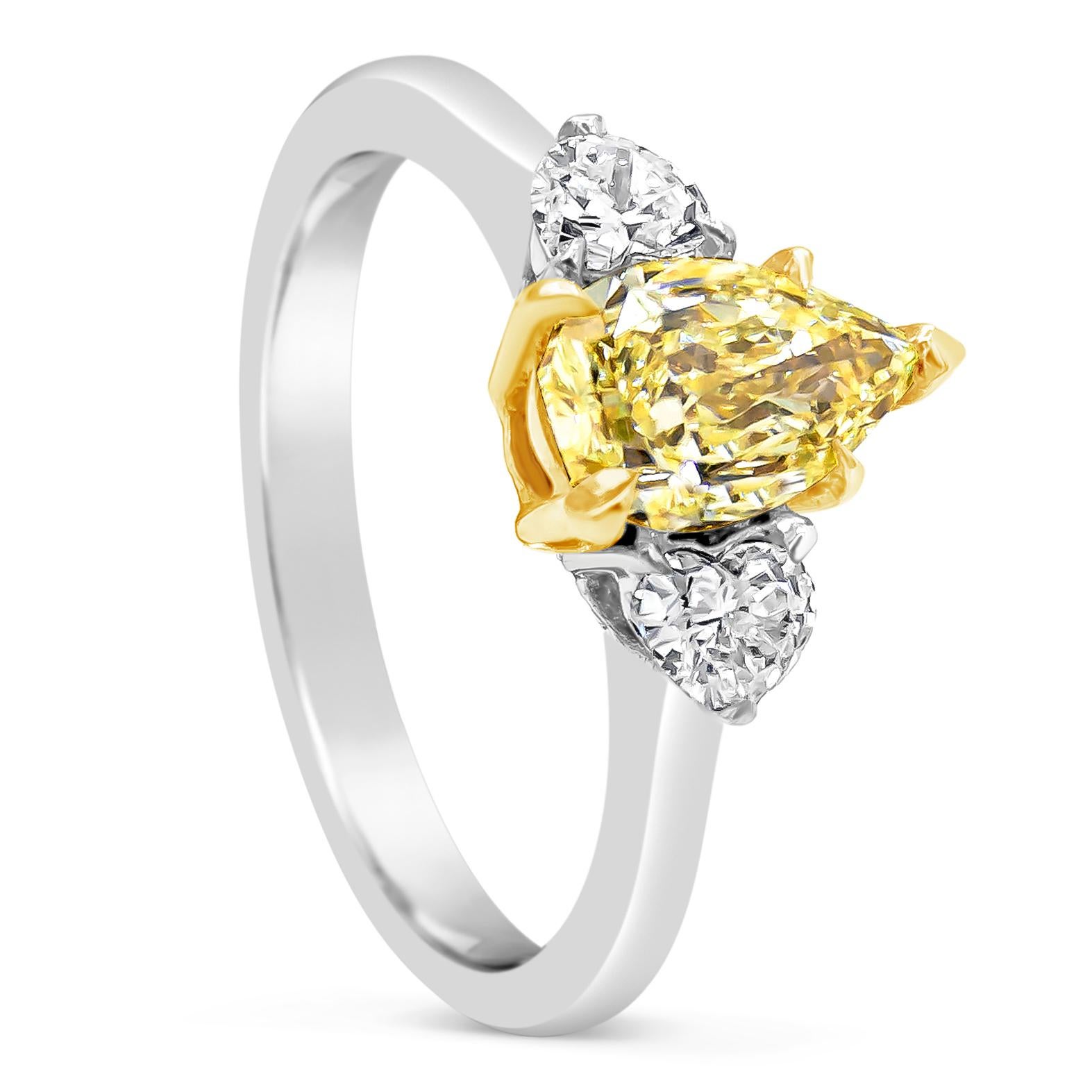 A unique engagement ring style showcasing a yellow pear shape diamond weighing 1.09 carats, set in a timeless five prong setting. Accented by two brilliant heart shape diamonds on each side weighing 0.30 carats total. Made in an 18K yellow gold and