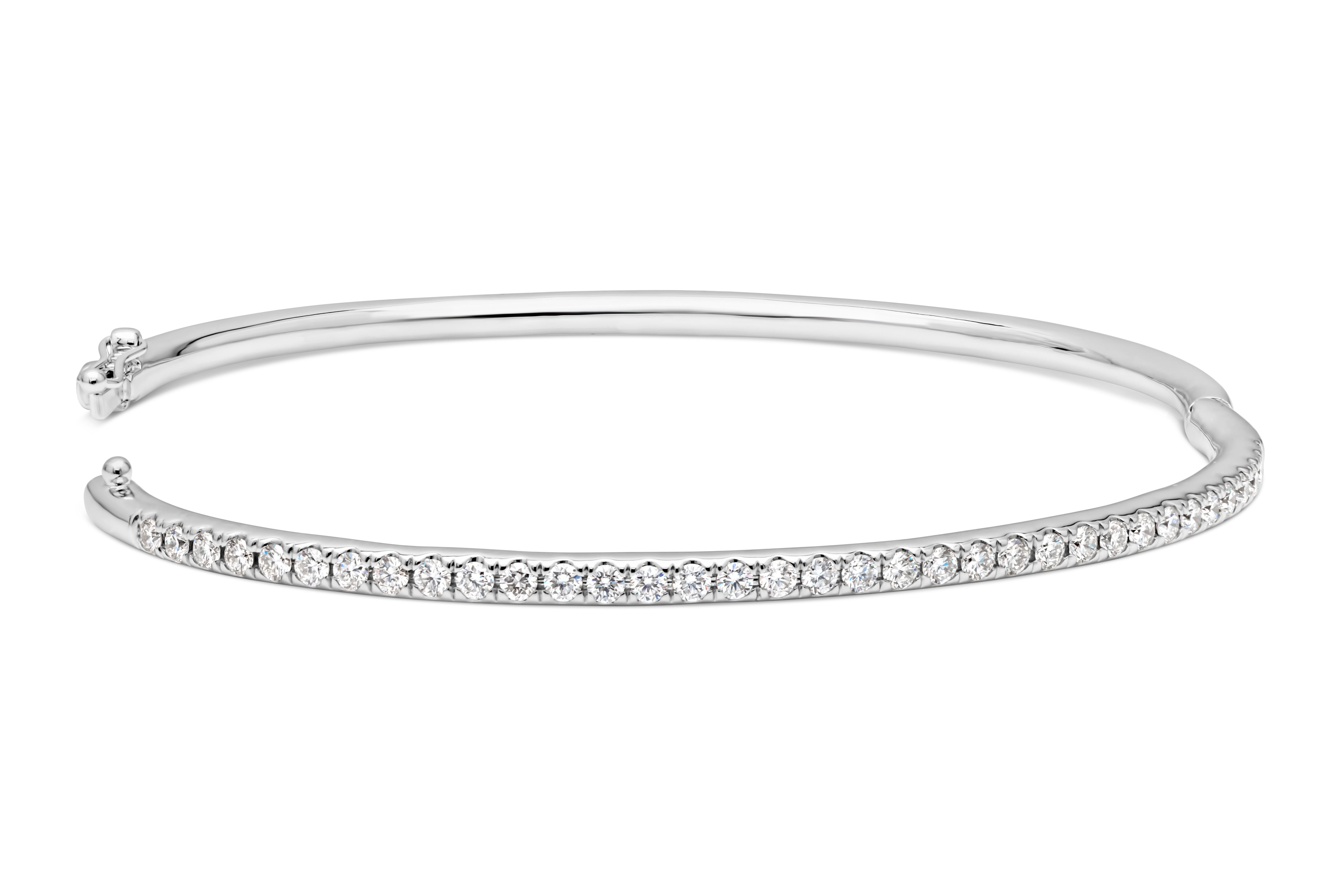 Showcasing a simple but elegant large wrist bangle bracelet set with 35 brilliant round cut diamonds weighing 1.10 carats total, F color and VS in clarity. Has a clasp to slip and wear the bangle securely. Finely made in 14K White Gold and 7.57