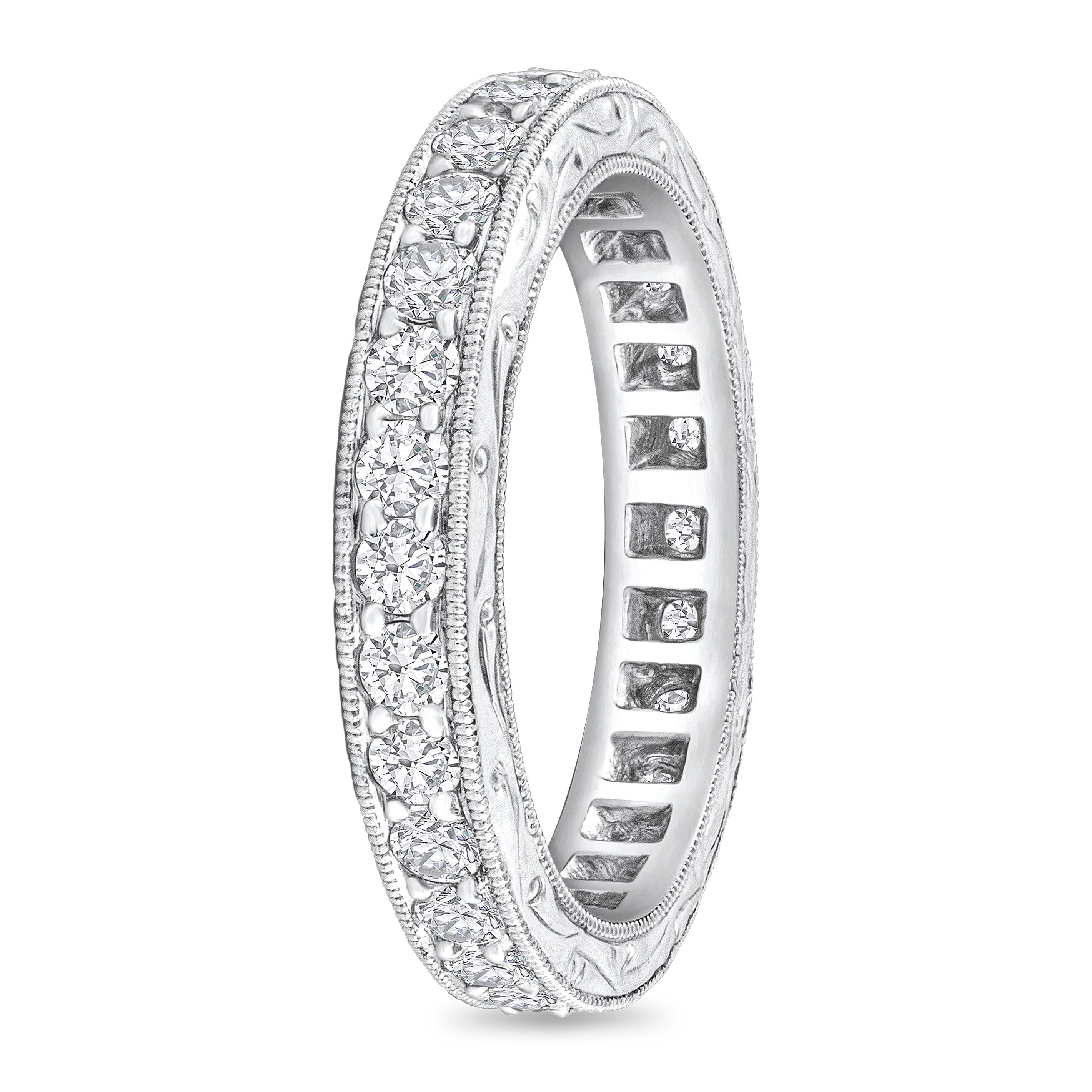 An expertly-crafted antique eternity wedding band ring showcasing brilliant round diamonds weighing 1.10 carats total. Channel-set and finished with intricate milgrain edges and a hand-engraved design. Made with Platinum, Size 6 US.