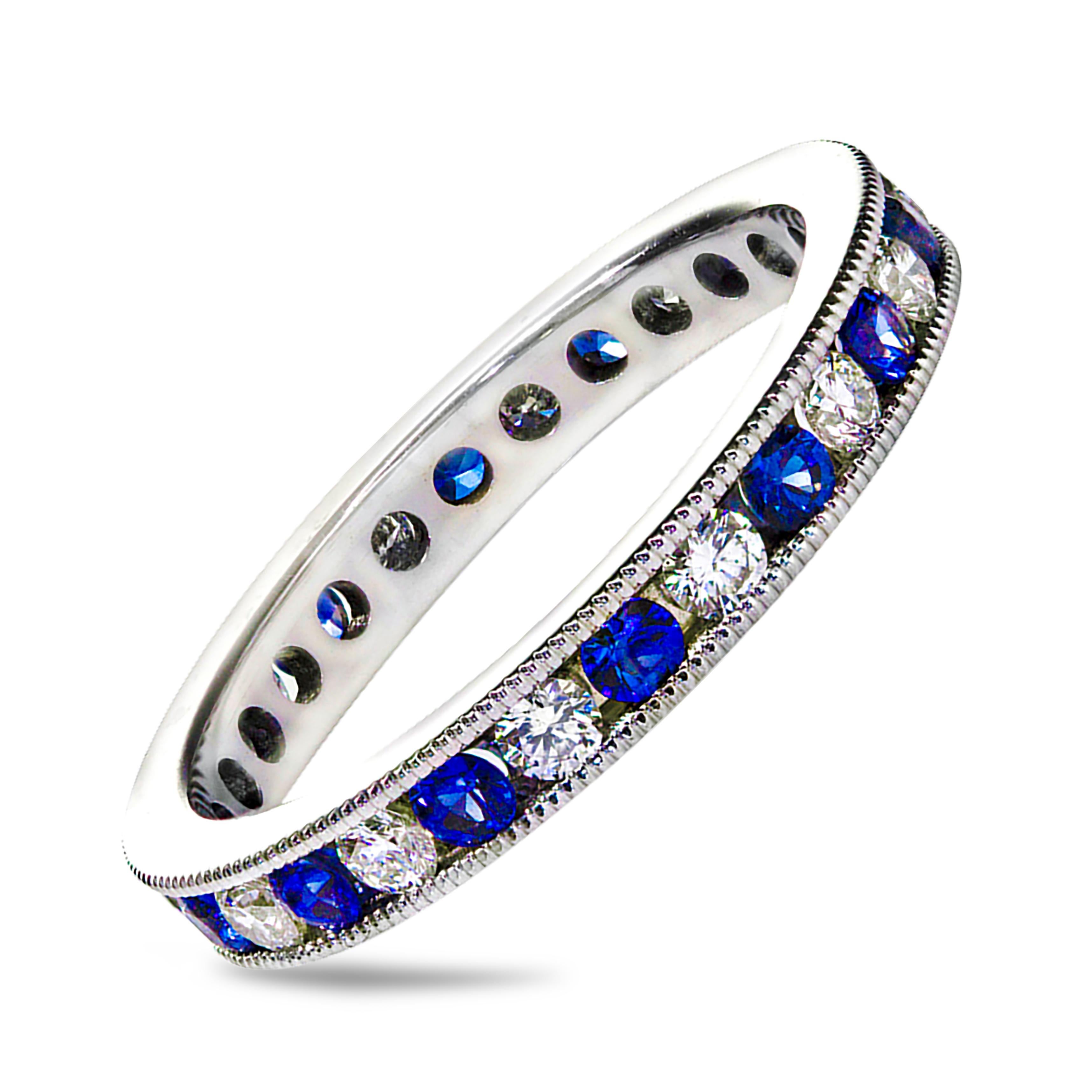 A well-crafted wedding band, showcasing round cut blue sapphires weighing 0.62 carats, alternating with round white diamonds weighing 0.50 carats total. Channel set and finished with intricate milgrain edges. Made with 18K white gold. Size 6.5 US.