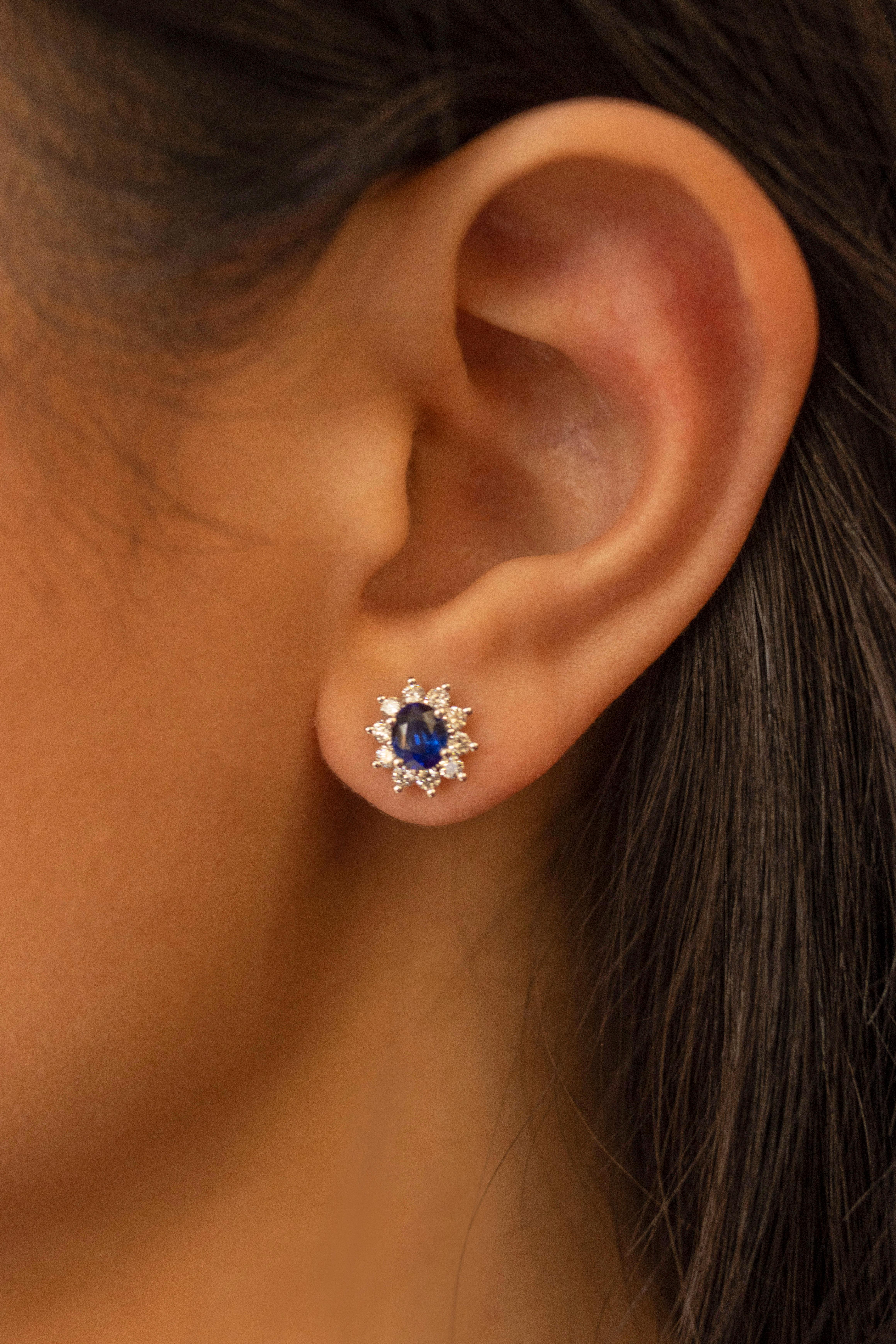 This beautiful pair of earrings showcases oval cut blue sapphire. Each sapphire is surrounded by a row of 20 brilliant round white diamonds weighing 0.57 carats total, G color, VS-SI clarity. Blue sapphire weigh 1.20 carats total. Made in 18 karat