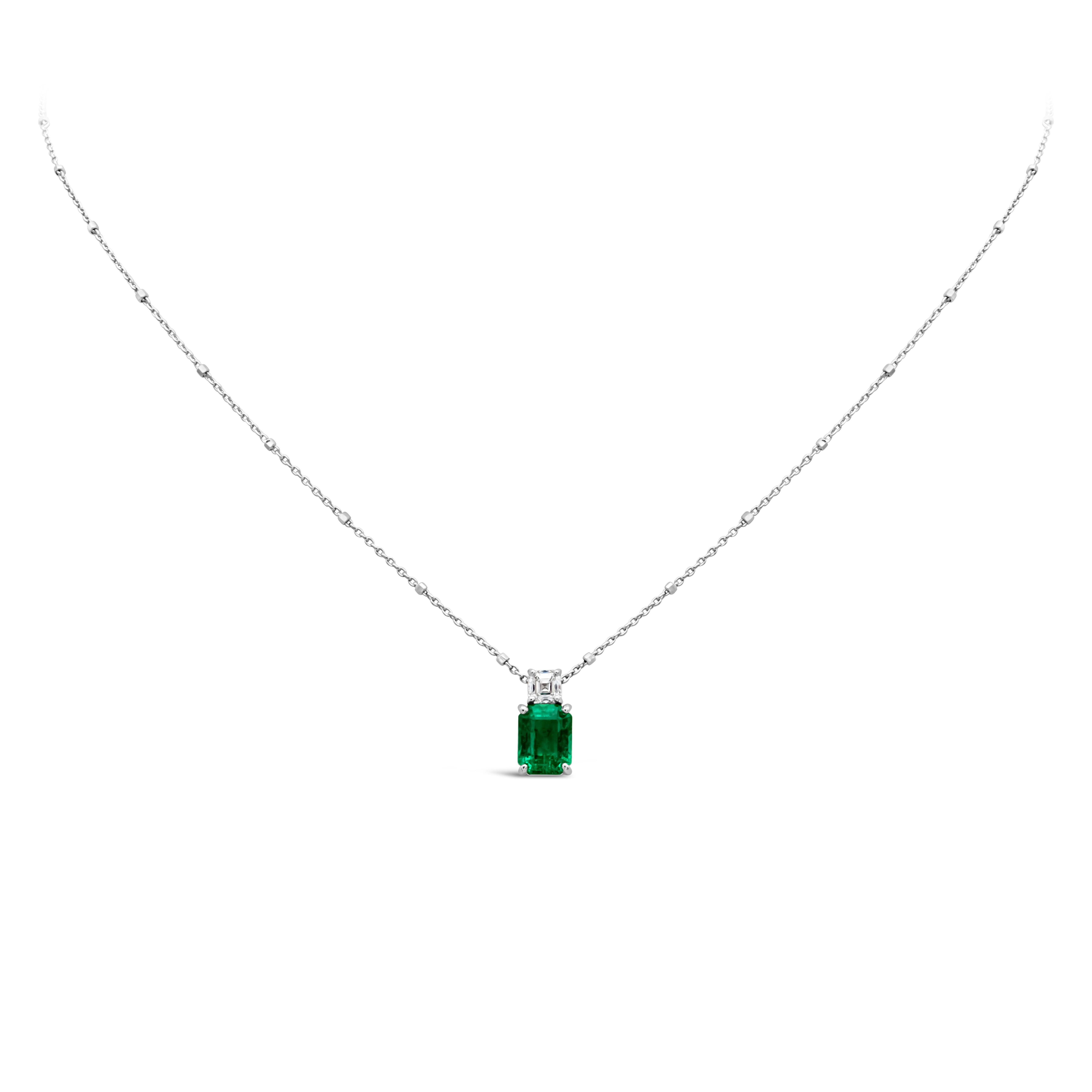 A charming color rich pendant necklace showcasing an emerald cut green emerald weighing 1.27 carats total, set in a four prong 18K white gold basket, accented by a single asscher cut diamond weighing 0.28 carat total. Suspended on a 14K White Gold