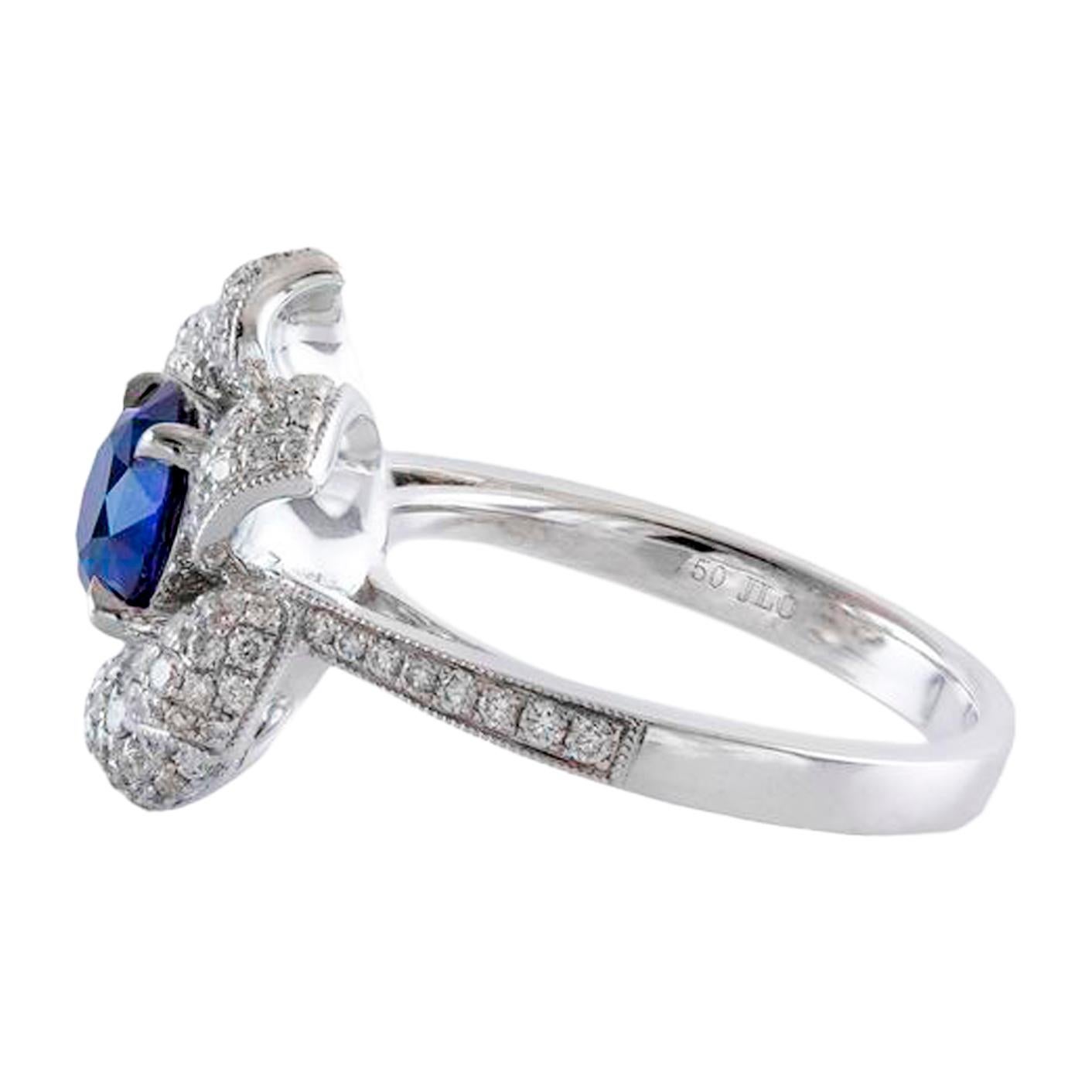 An elegant fashion ring design showcasing a round cut blue sapphire center stone weighing 1.35 carat total, set in a four prong basket. Surrounded by six flower petals encrusted with brilliant round diamonds weighing 0.78 carats, and accenting