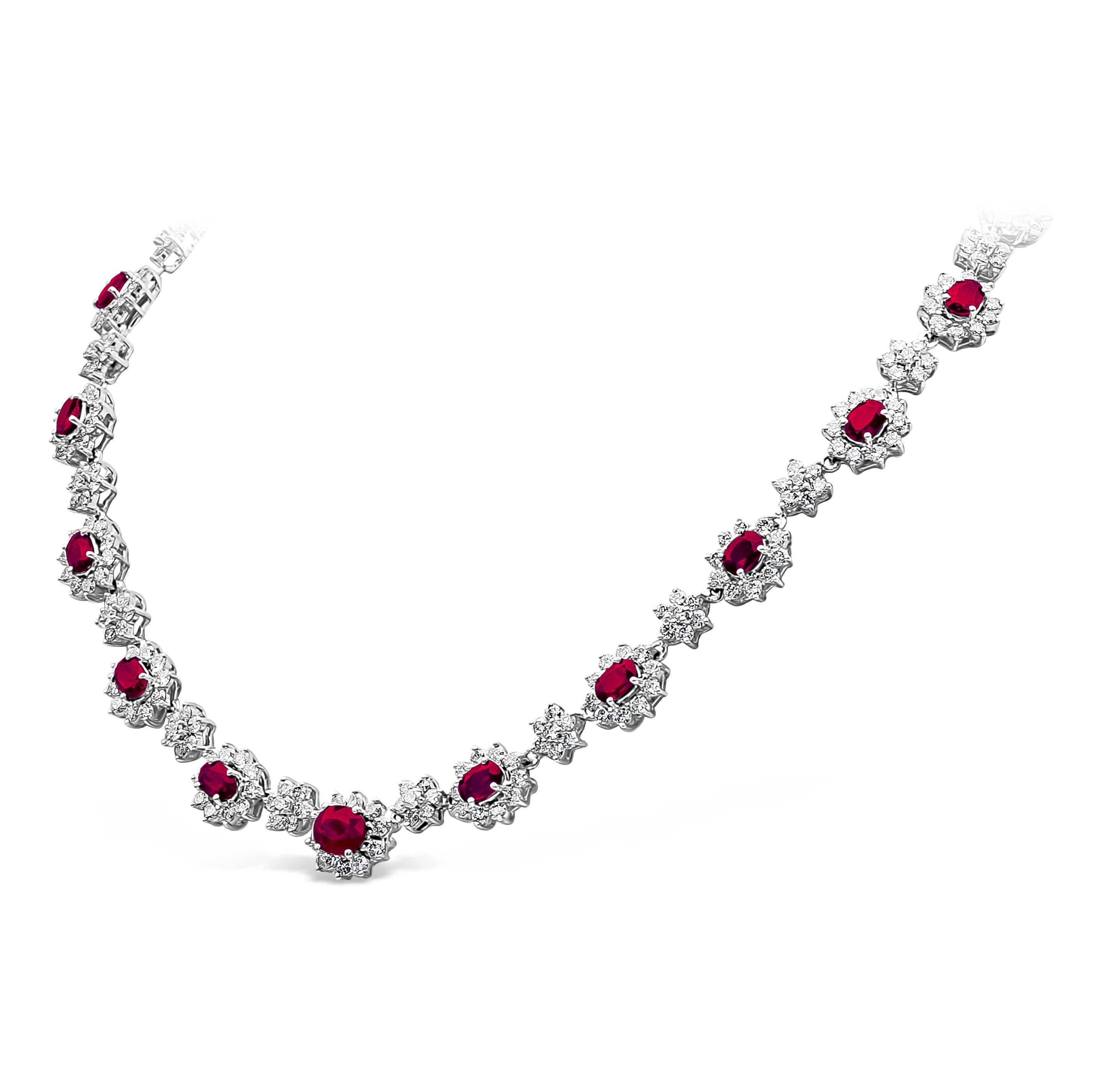 A vintage style collar necklace, showcasing vibrant oval cut natural rubies weighing 14.01 carats total, surrounded with a halo of round brilliant cut diamonds. Elegantly spaced by more round brilliant cut diamonds, set on a floral motif design.