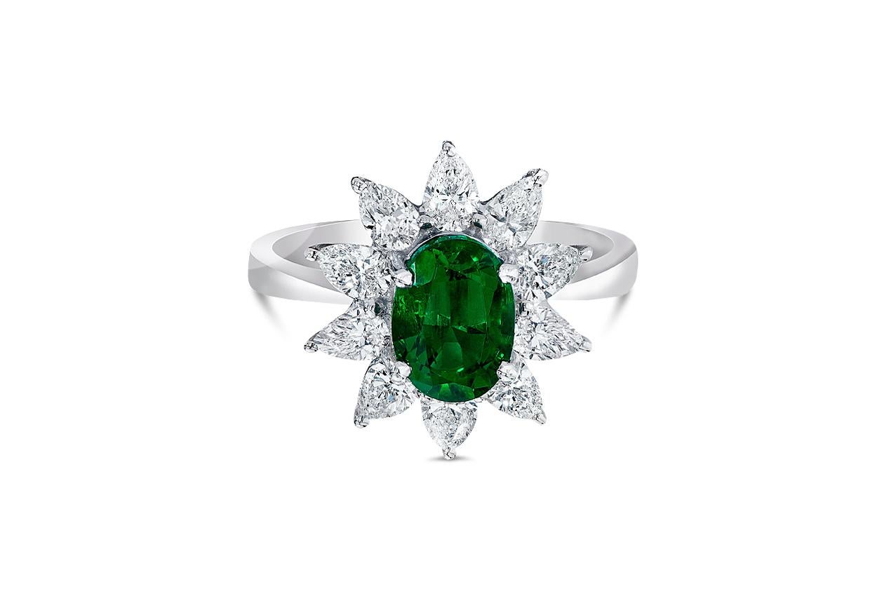 Ein atemberaubender Verlobungsring mit einem grünen Smaragd im Ovalschliff von 1,48 Karat, der elegant von 10 funkelnden birnenförmigen Diamanten mit einem Gesamtgewicht von 1,06 Karat umgeben ist und mit einem Blumenmotiv besetzt ist. Fein