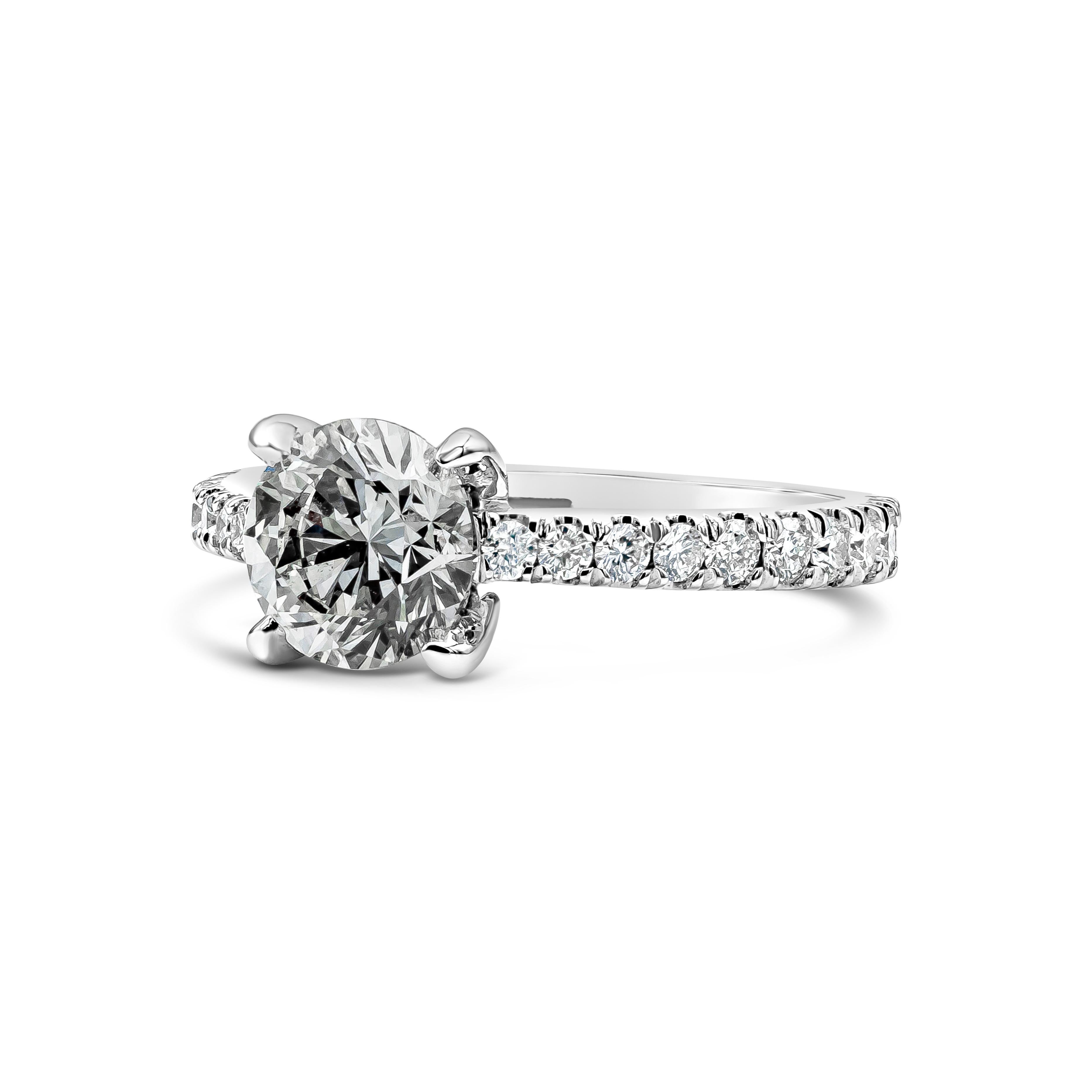 A classic engagement ring, showcasing a 1.50 carats round brilliant cut diamond with H color and SI2 clarity, set on four rounded prongs. Accented by 20 round cut diamonds weighing 0.51 carats total in a pavé setting with a half-eternity design.