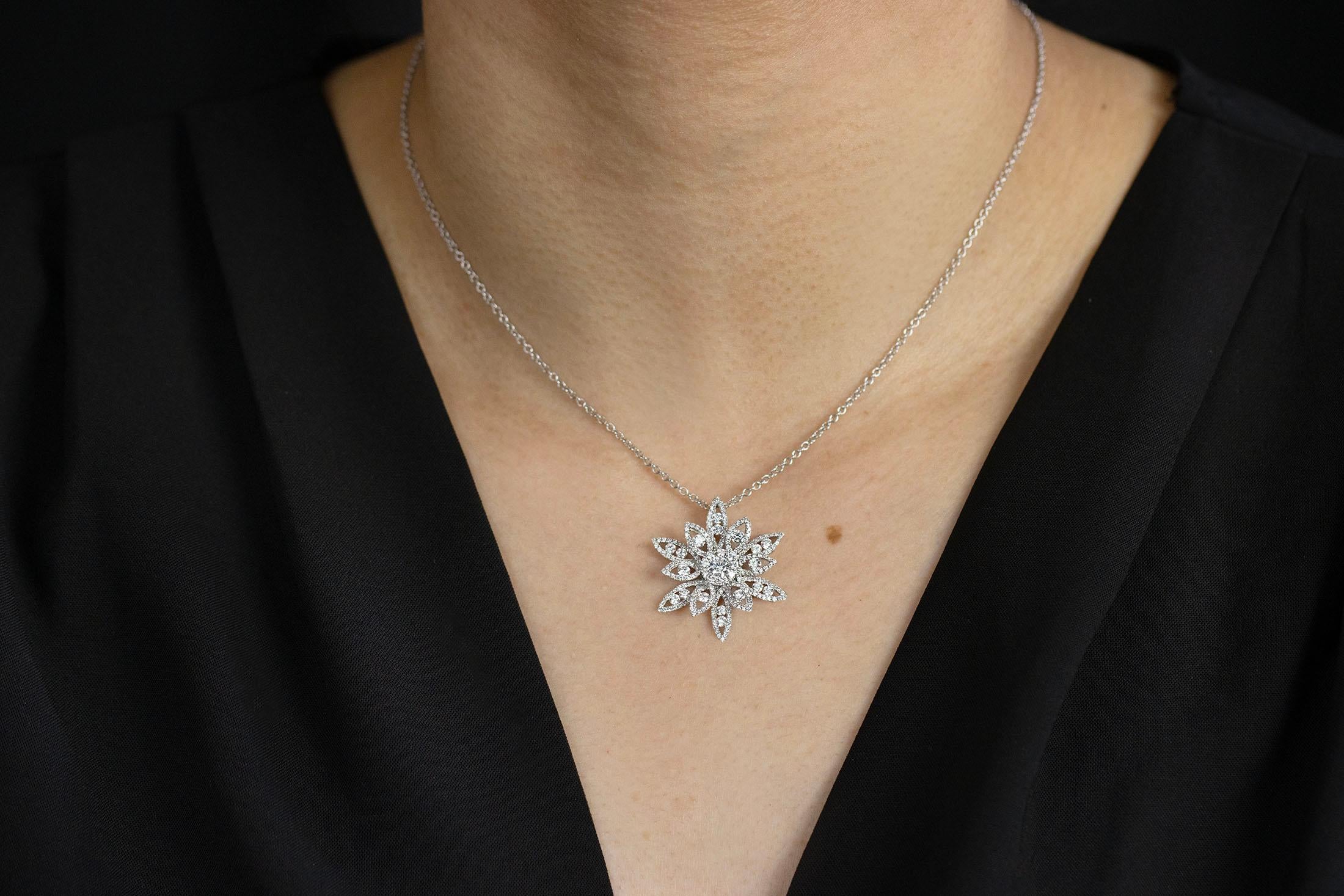 A brilliant pendant necklace showcasing a 0.19 carats diamond center stone surrounded by flower petals overlaid with sparkling melee diamonds. Accent diamonds weigh 1.39 carats total. Set in 18K white gold. Suspended on an 18 inch adjustable white