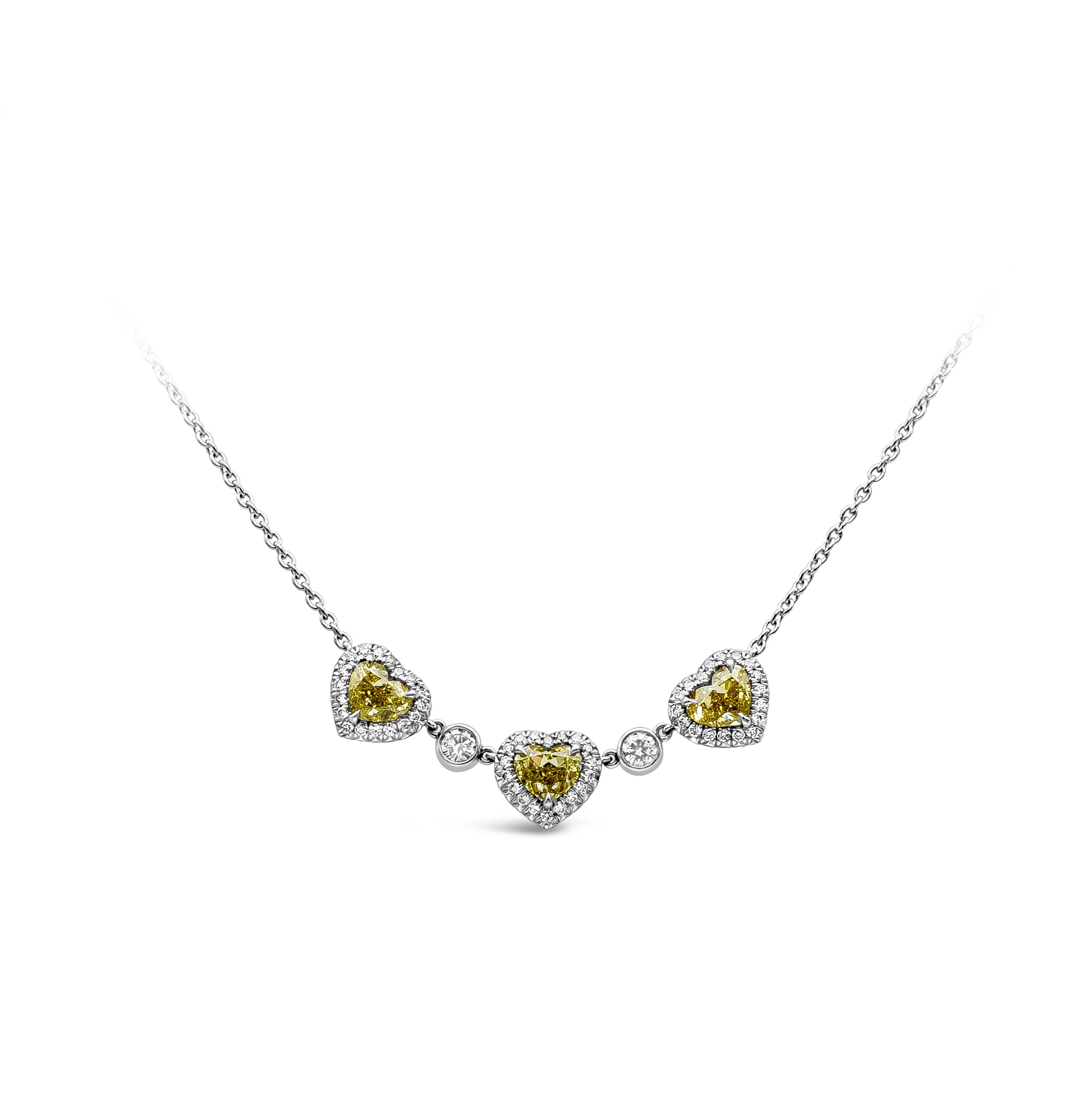 A simple but elegant diamond pendant necklace showcasing a row of three heart shape fancy intense yellow diamonds accented by bright round diamonds. Two round diamonds bezel are in between the heart shape diamonds set in platinum. Fancy intense