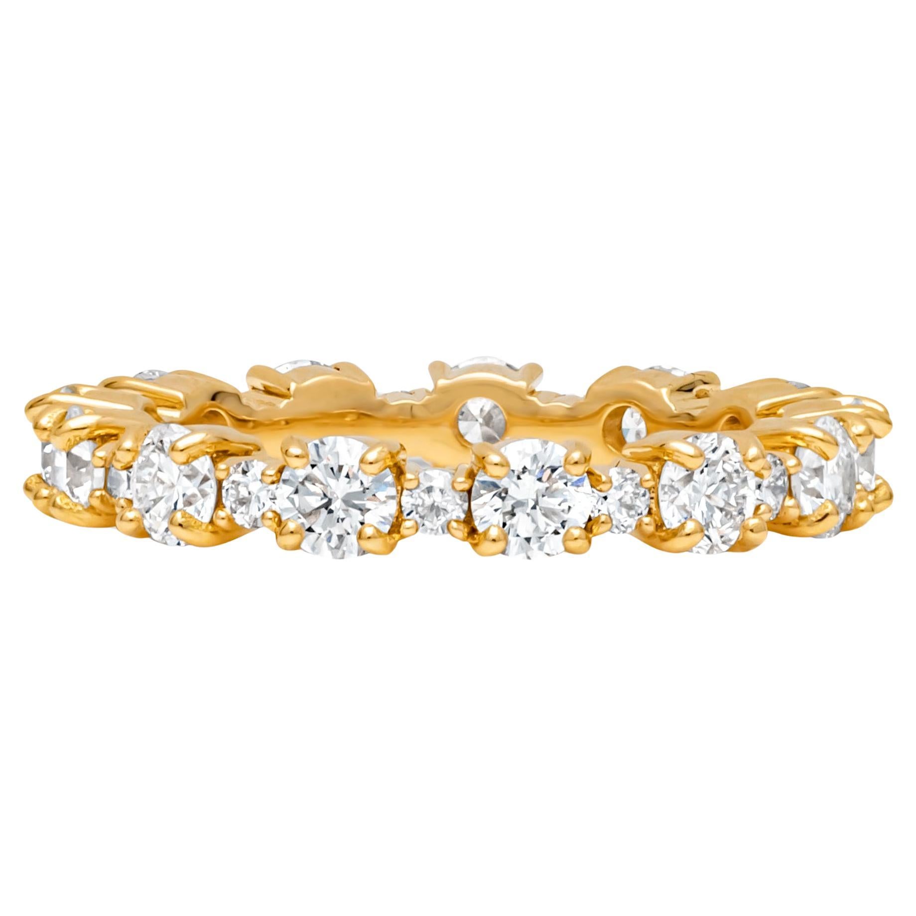 A uniquely-designed eternity wedding band showcasing a row of round brilliant diamonds elegantly spaced by smaller round melee diamonds weighing 1.77 carats total, H Color and VS in Clarity. Set in a classic four prong basket setting and Made in 18K