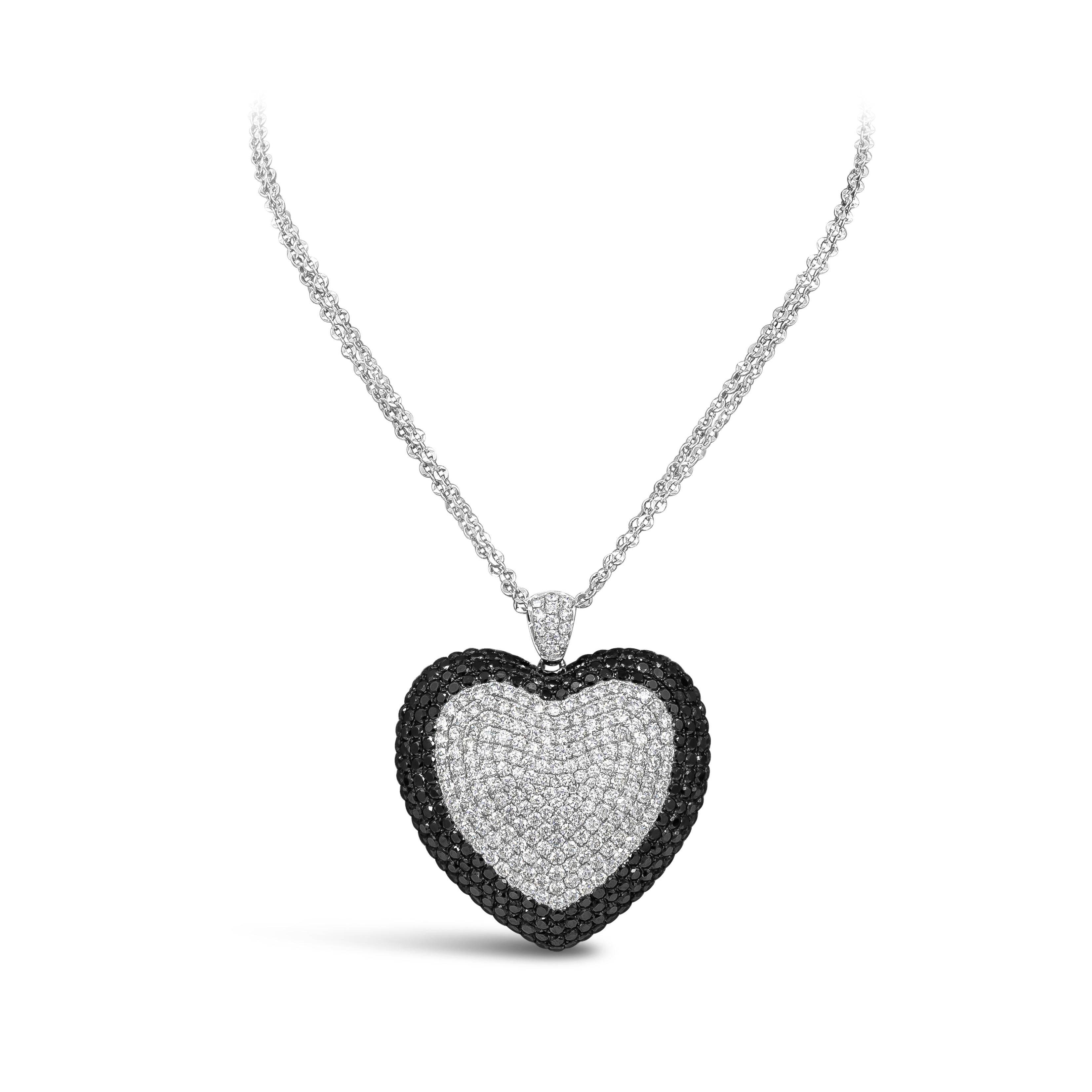 Features an oversized heart shape pendant pave set with black diamonds on the outer edges weighing 10 carats total. Encrusted with white diamonds in the middle weighing 7.70 carats total. Suspended on a 18inch adjustable chain and finely made in 18k