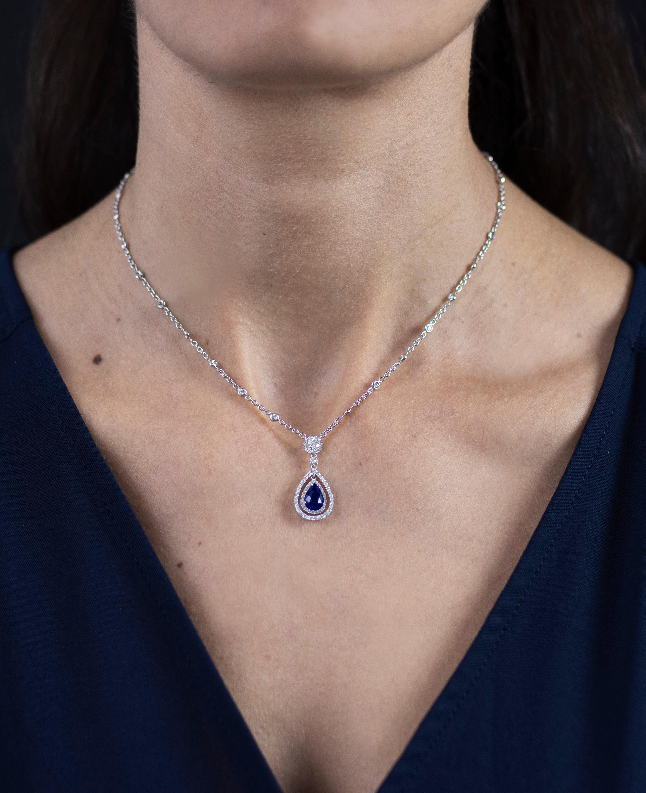 A classic pendant necklace showcasing a pear shape blue sapphire weighing 1.78 carats total. Embellished by two rows of round diamonds, weighing 1.28 carats total. Suspended on a round cut diamond halo surmount attached to a diamonds by the yard