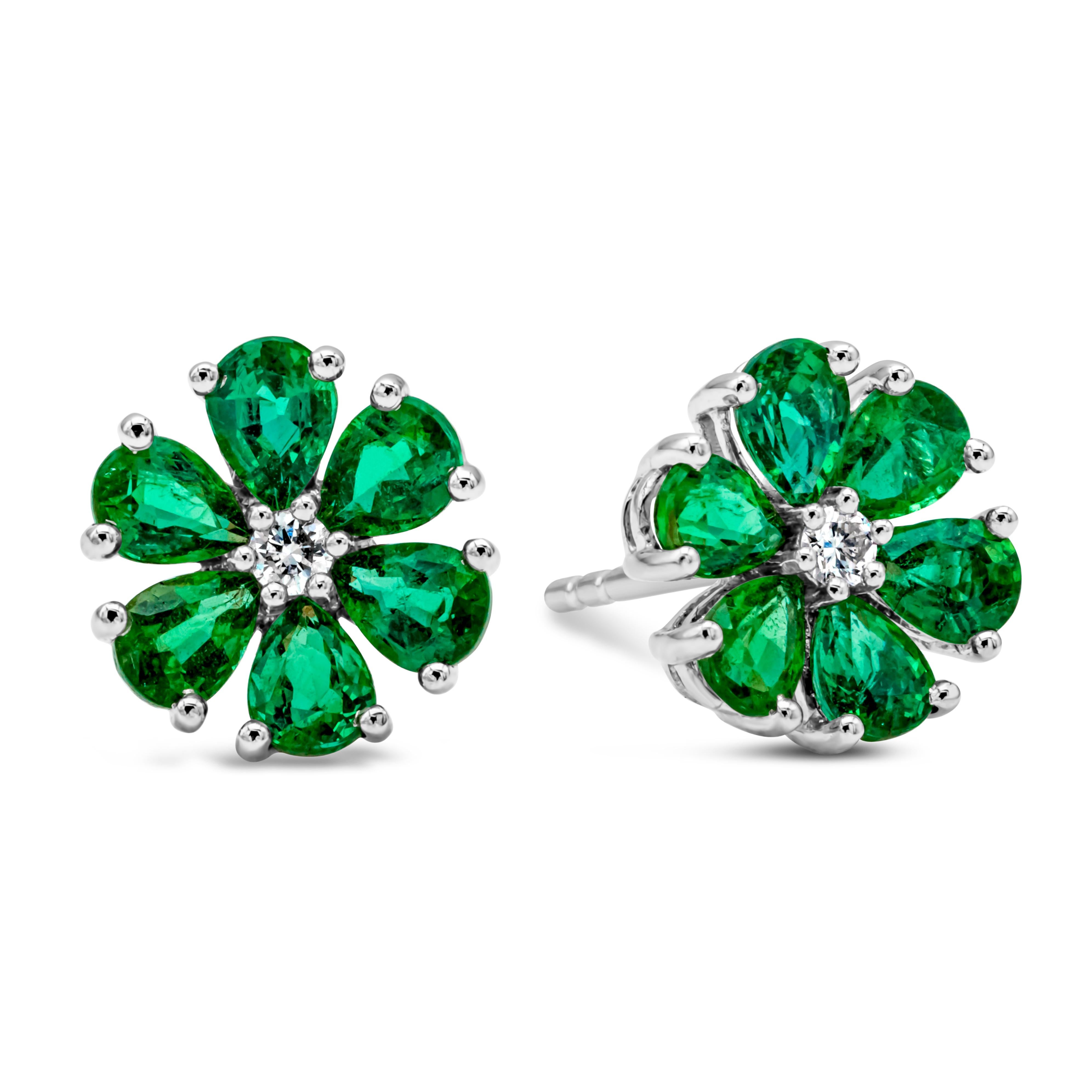 A very beautiful pair of stud earrings featuring a round shape brilliant diamond center weighing 0.07 carats total, F color, VS in clarity and set in a six prong basket setting. Accented with color-rich pear shape green emerald set in a floral-motif