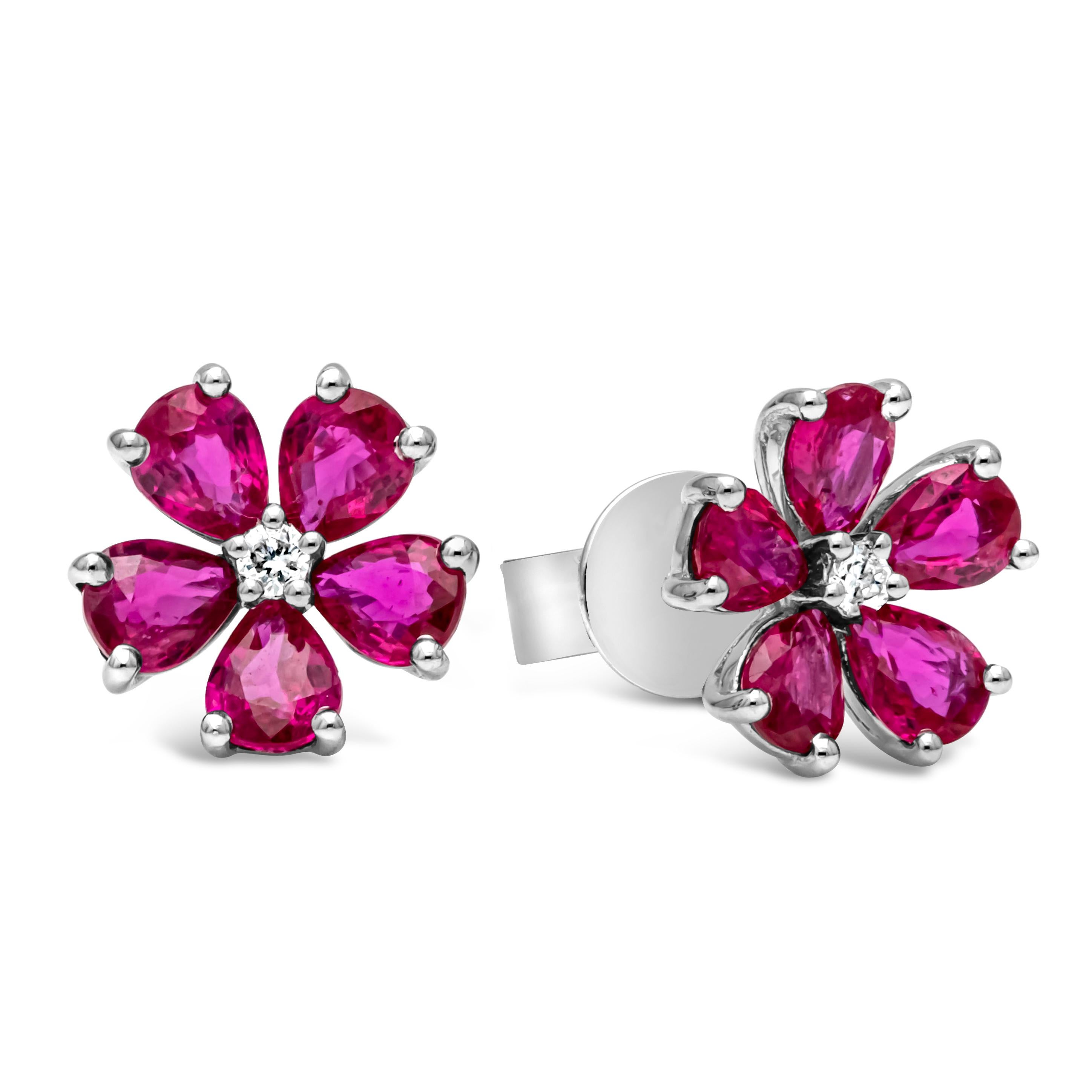 A beautiful pair of stud earrings featuring a round shape brilliant diamond center weighing 0.04 carats total, F color, VS in clarity and set in a five prong basket setting. Accented with color-rich pear shape ruby set in a floral-motif design and