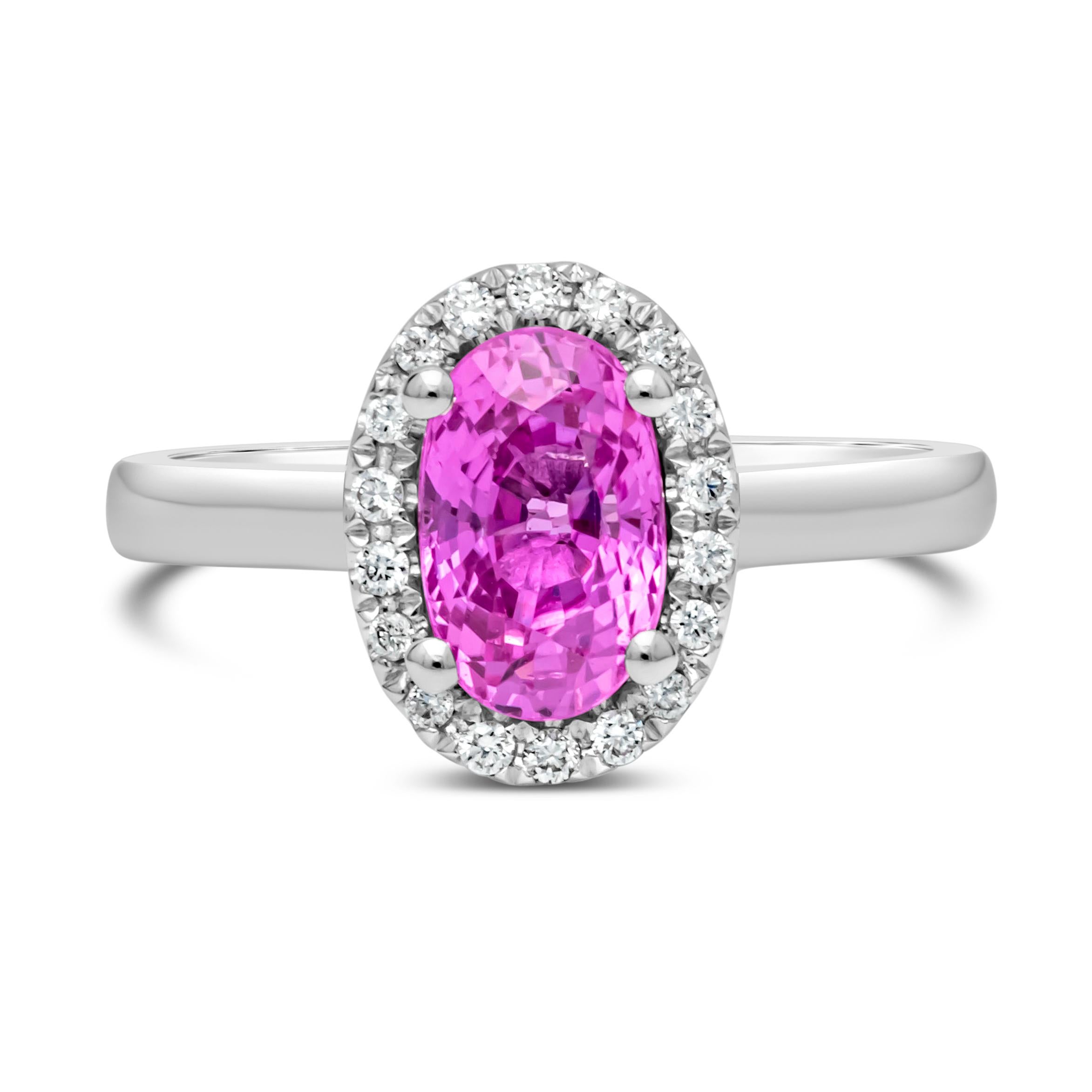 This versatile and beautiful halo engagement ring style showcasing an oval cut pink sapphire weighing 1.95 carats total, set in a classic four prong basket setting. Elegantly surrounded by a row of 32 brilliant round diamonds weighing 0.22 carats