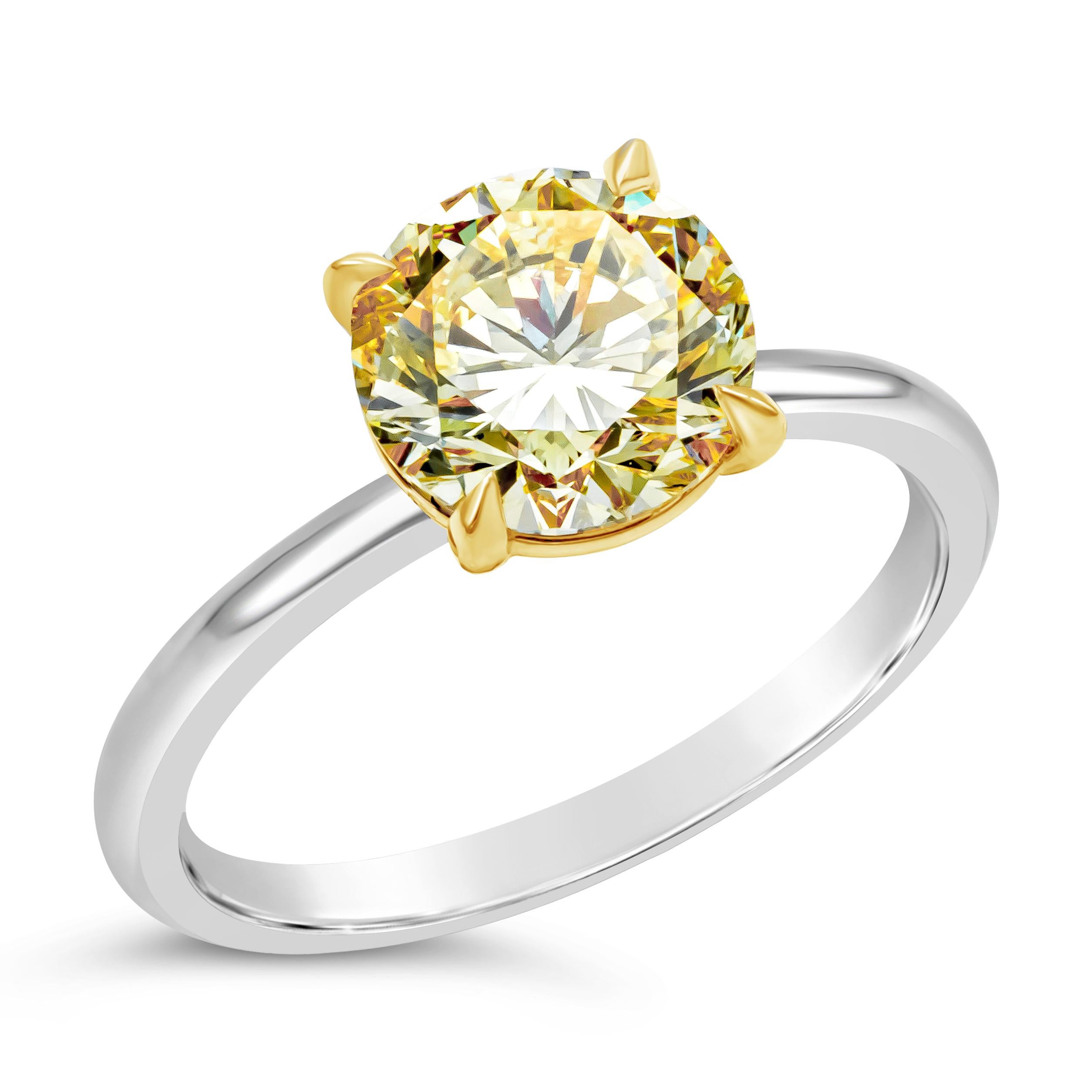A classic and timeless solitaire diamond ring showcasing a single fancy light yellow round brilliant diamond weighing 2.00 carats. Diamond set in 18 karat yellow gold prongs, mounted on polished platinum ring. Accompanied with a GIA report