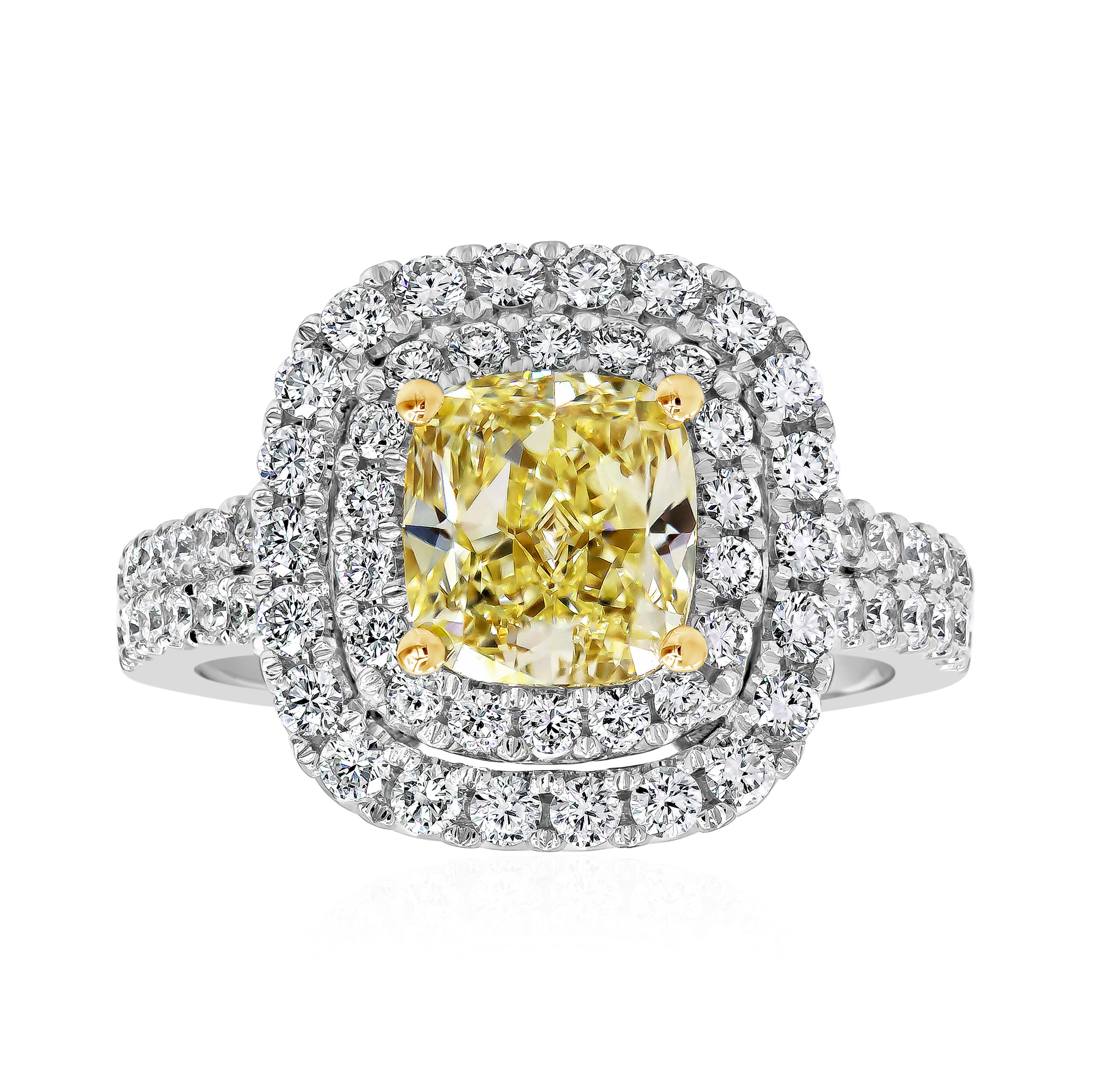 A beautiful engagement ring, showcasing a 2.02 carats fancy yellow diamond certified by GIA as W-X color and SI1 clarity, set on four rounded prongs made of 18K yellow gold. Surrounded by a double halo of round brilliant cut diamonds and accented by