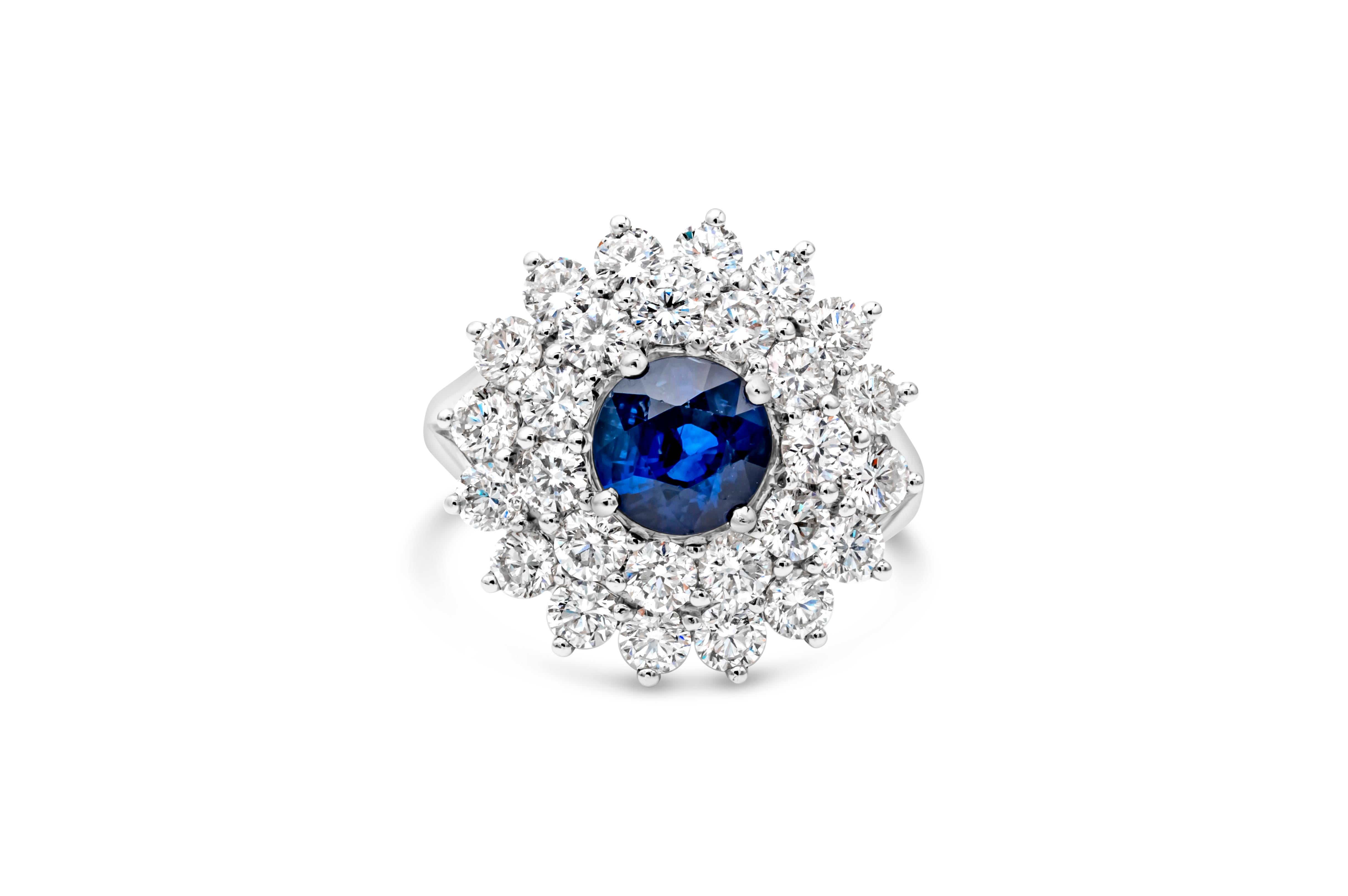 This elegant and stunning engagement ring style showcasing a round cut blue sapphire weighing 2.13 carat total, set in a classic four prong basket setting. Surrounded by brilliant round diamonds in a double halo design weighing 2.85 carats total,