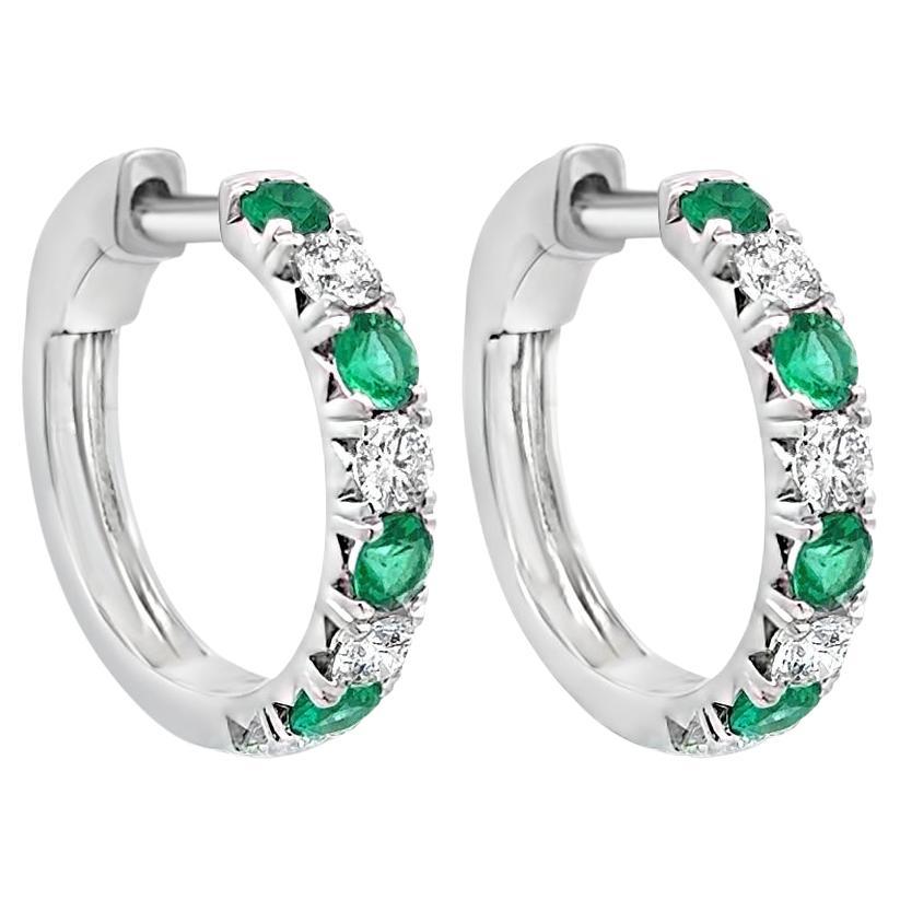 Une élégante paire de boucles d'oreilles, mettant en valeur une rangée d'émeraudes et de diamants ronds de taille brillant pesant respectivement 1,06 carat et 1,08 carat. Les pierres sont serties en alternance. Magnifiquement réalisé en or blanc 18