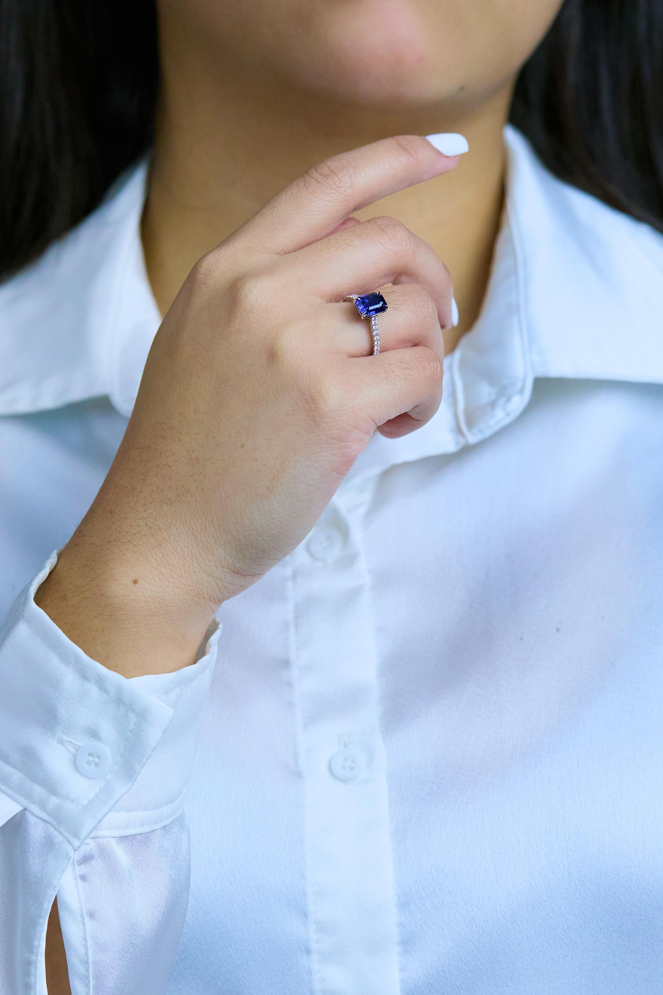 Un anillo de compromiso atemporal, con un zafiro azul profundo talla esmeralda de 2,22 quilates, engastado con cuatro garras. Acentuado por diamantes redondos de talla brillante con un peso total de 0,26 quilates, engastados en un diseño de media
