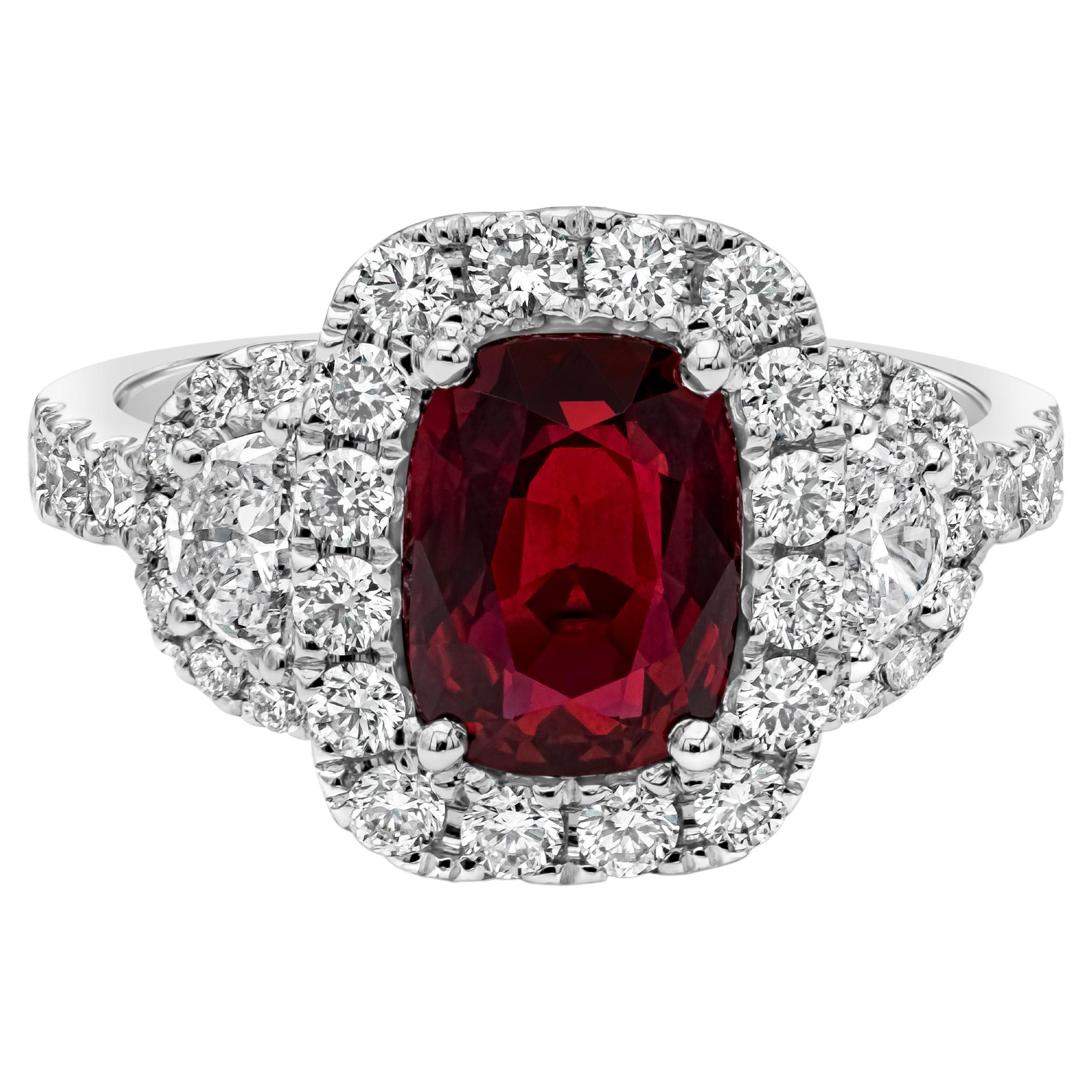 A contemporary piece of jewelry showcasing a GRS certified color-rich cushion cut ruby center stone weighing 2.32 carats total, set in a classic four prong setting in a halo design. Flanked by two half moon diamonds on each side weighing 0.29 carats