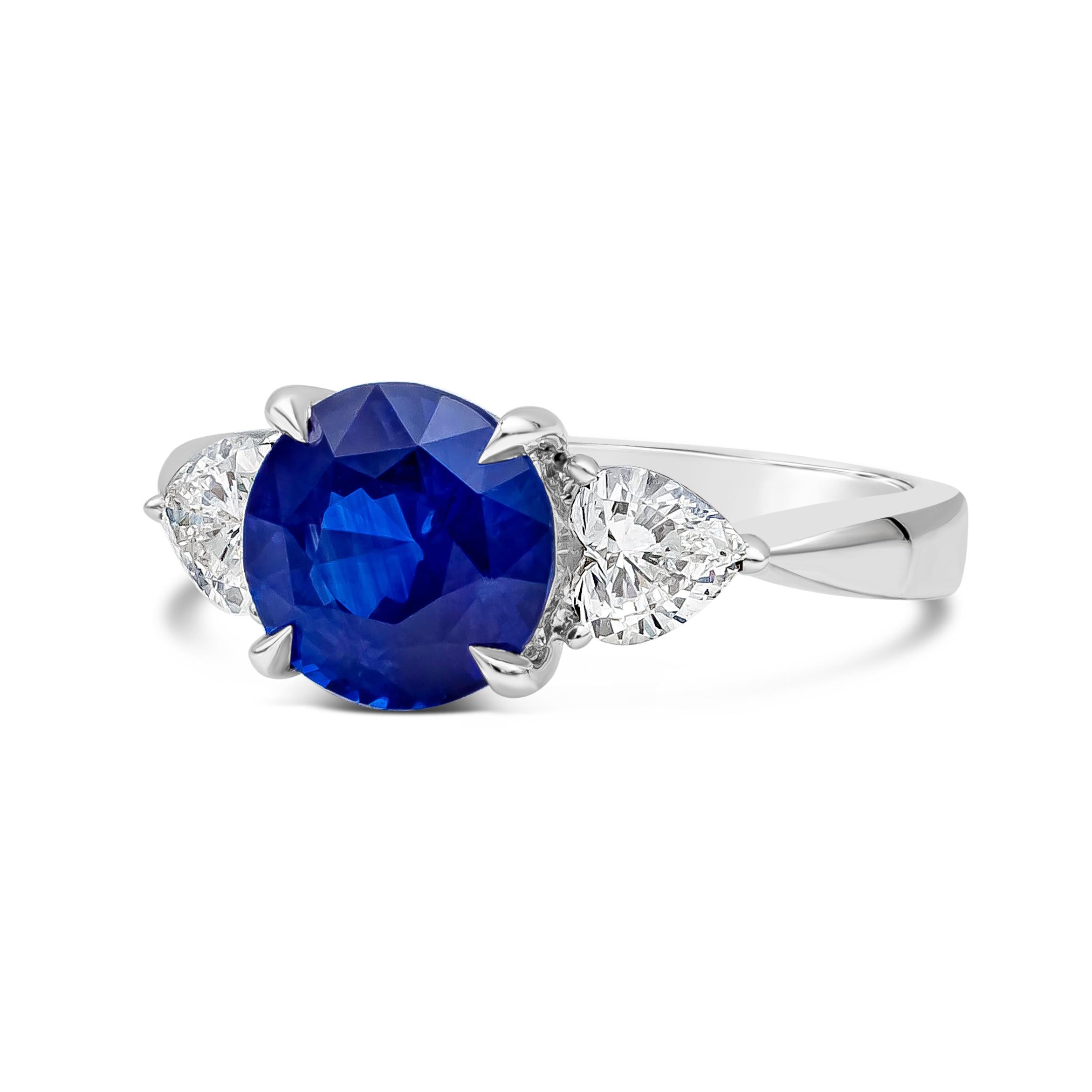 A classic and unique three-stone engagement ring, showcasing a 2.77 carats round cut blue sapphire. Accented by two heart shape diamonds weighing 0.65 carat total. Set on a chic knife-edge shank made of platinum. Size 6.5 US, resizable upon