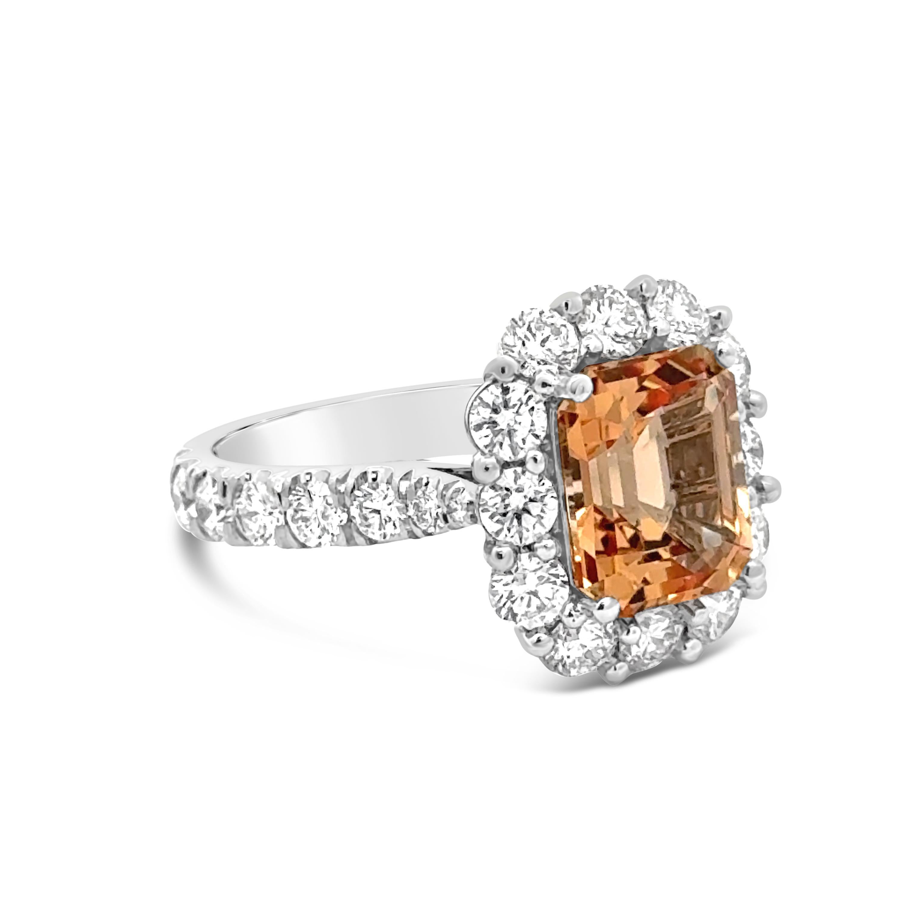 A gorgeous engagement ring, featuring a vibrant 3.00 carats emerald cut imperial topaz. Surrounded by a halo of round brilliant cut diamonds and accented by graduating round brilliant cut diamonds on the shank in a half-eternity design. Accent