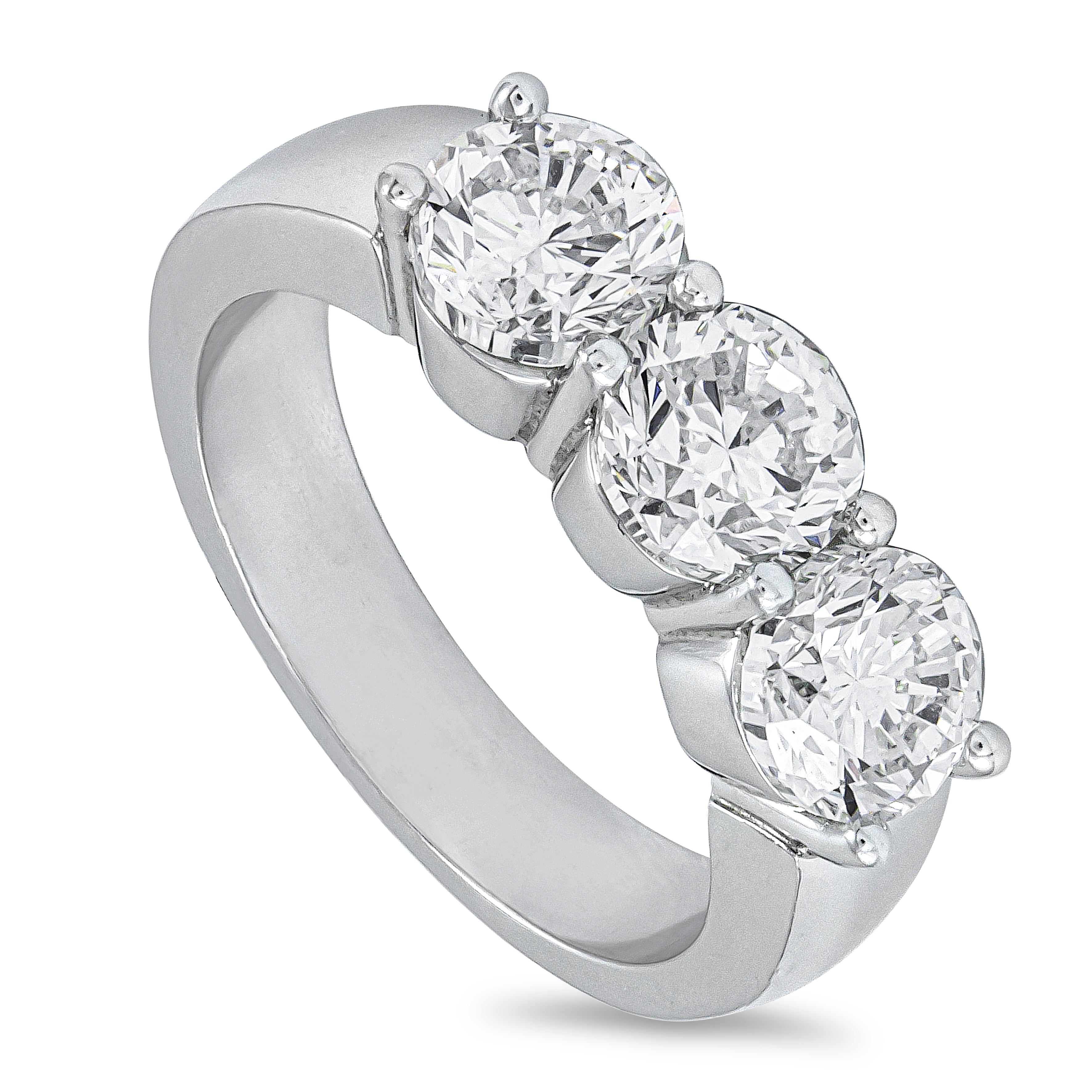 A classic three-stone wedding band ring, featuring three round brilliant cut diamonds weighing 3.01 carats total with I color and VS2 clarity, set on a shared prong setting. Finely made with a platinum mounting, 5.9 mm in width. Size 6 US, resizable