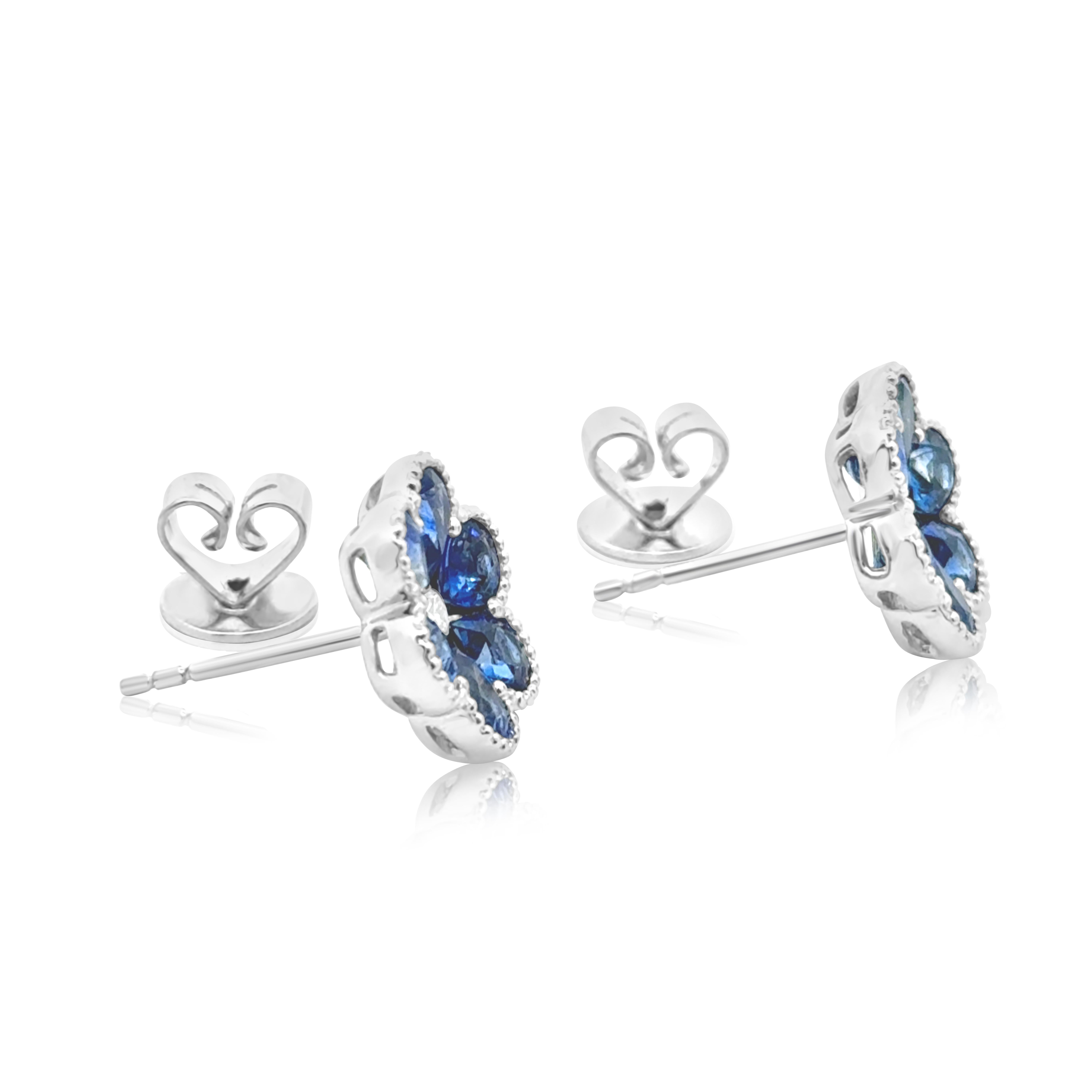 A lovely pair of stud earrings, featuring 12 pear shape sapphires weighing 3.04 carats total, set with a beautiful flower motif on a beaded bezel setting. Accented by a round brilliant cut diamond, set at the center of the flower. The accent