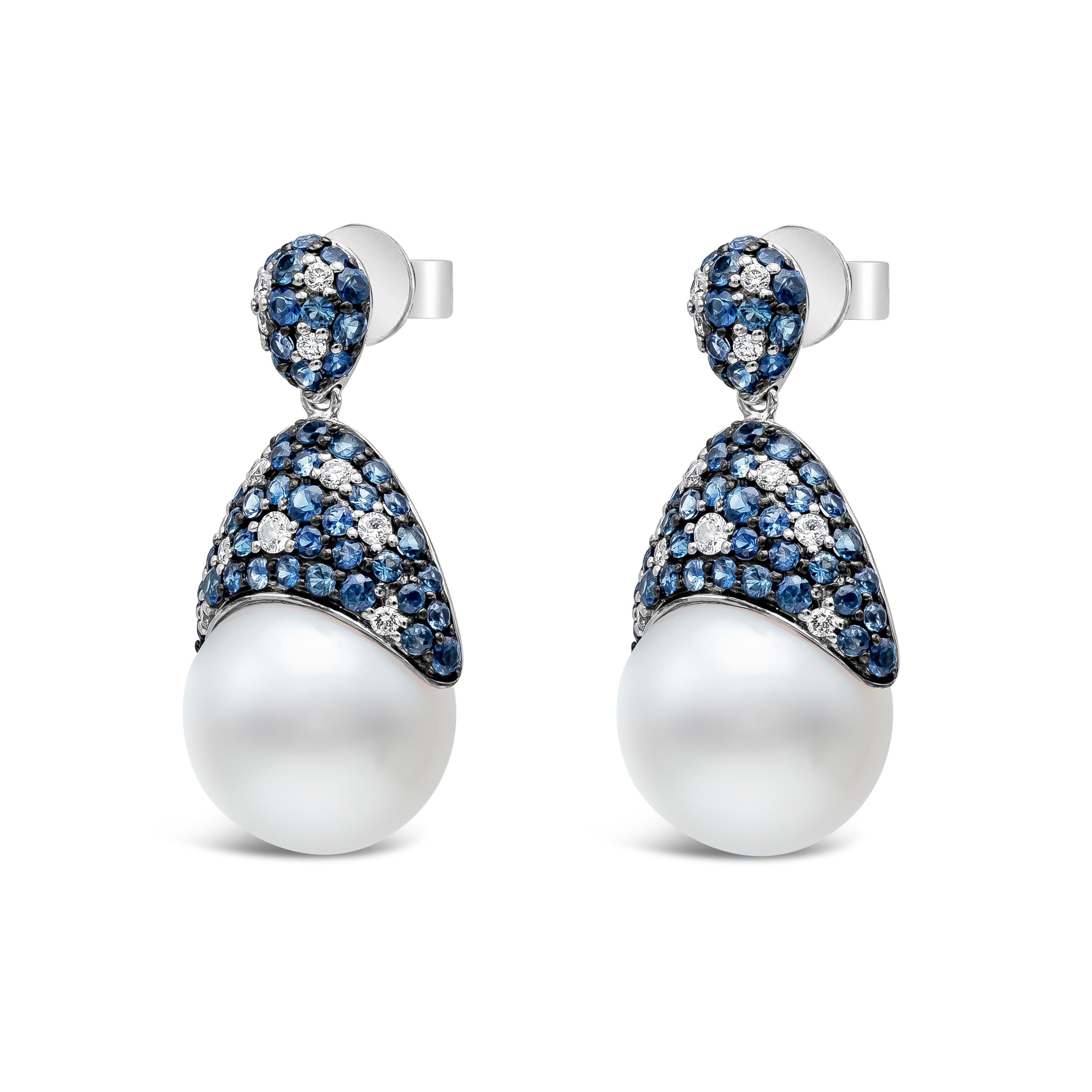 Ces boucles d'oreilles sont composées de perles des mers du Sud de 13 à 14 mm de diamètre et d'un motif incrusté unique. Il comprend 106 saphirs bleus pesant 3,07 carats au total et 26 diamants ronds pesant 0,45 carat au total. Fabriqué avec de l'or