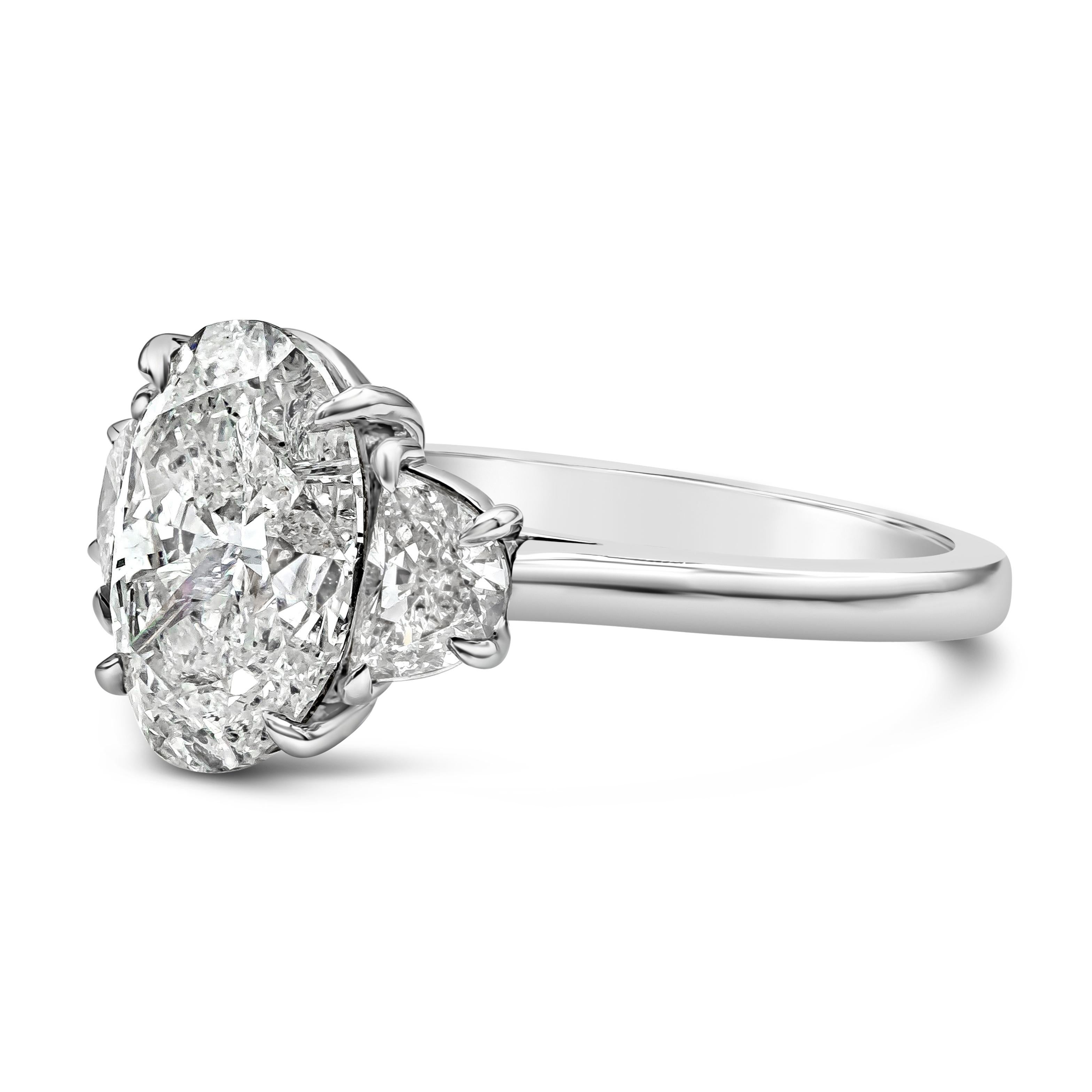 A classic and vibrant three-stone engagement ring, showcasing a 3.23 carats oval cut diamond certified by GIA as I Color and I2 clarity, set on a classic four claw prong basket setting. Flanked by two half moon shape diamonds weighing 0.69 carat