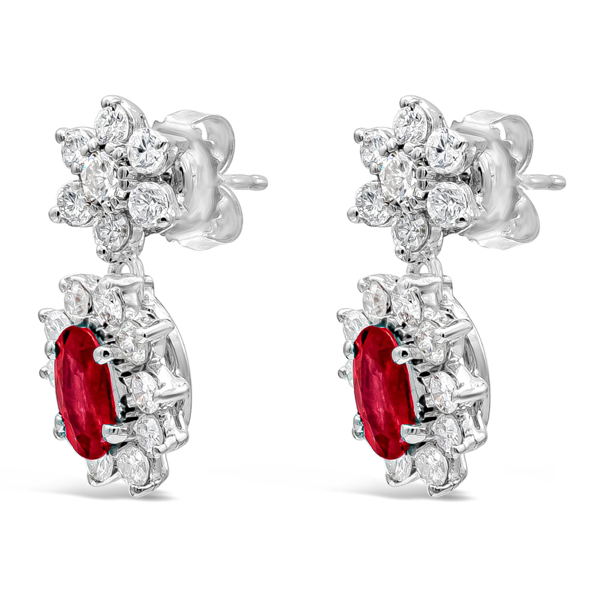 Elegant and chic classic drop earrings showcasing a beautiful oval cut ruby surrounded by round  diamonds, Suspended on a floral-motif round diamond halo. Ruby weighs 1.70 carats and diamonds weigh 1.74 carats total. Made with 18K White Gold

Style