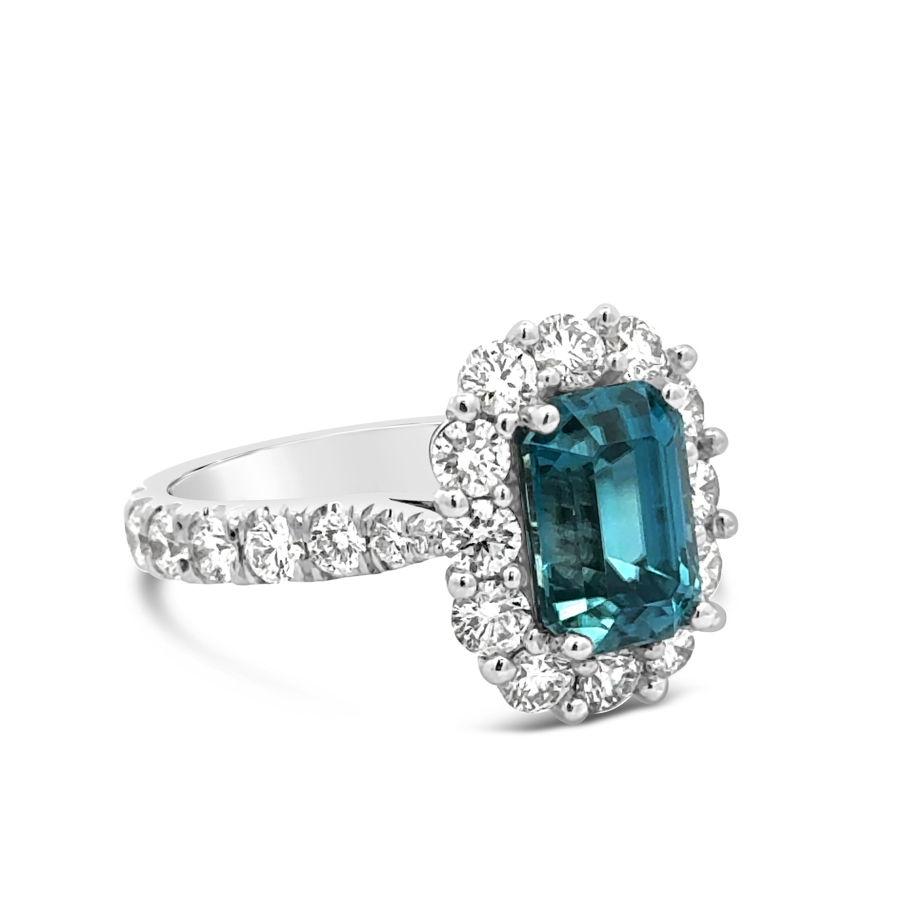 A stunning engagement ring, featuring a vibrant 3.45 carats emerald cut blue zirconia. Surrounded by a halo of round brilliant cut diamonds and accented by graduating round brilliant cut diamonds on the shank in a half-eternity design. Finely made