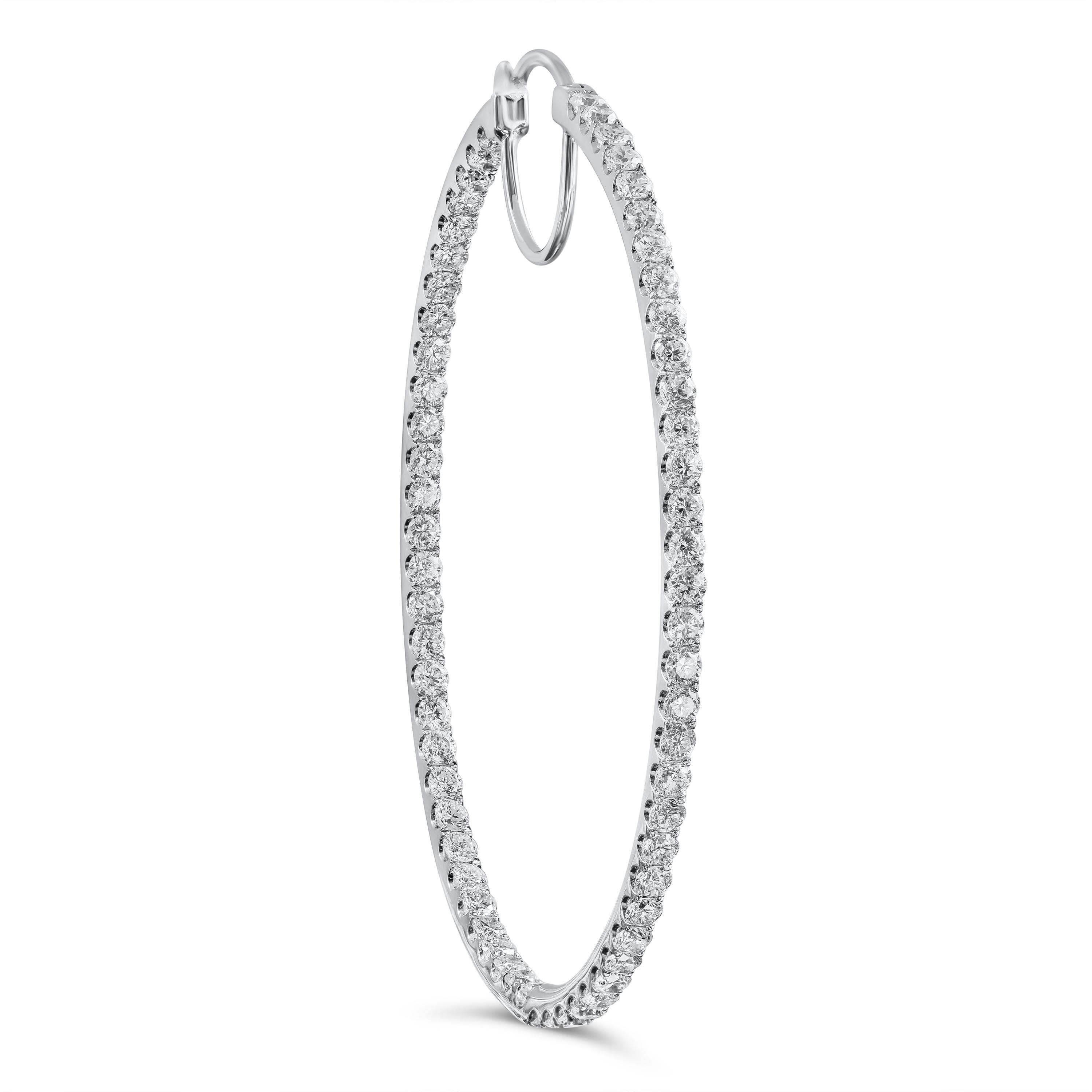 A brilliant pair of hoop earrings showcasing a row of sparkling round diamonds set in a scalloped pave design in 18k white gold. The earrings have a chic oval-shaped design. Diamonds weigh 3.67 carats total. Approximately 2 inches in