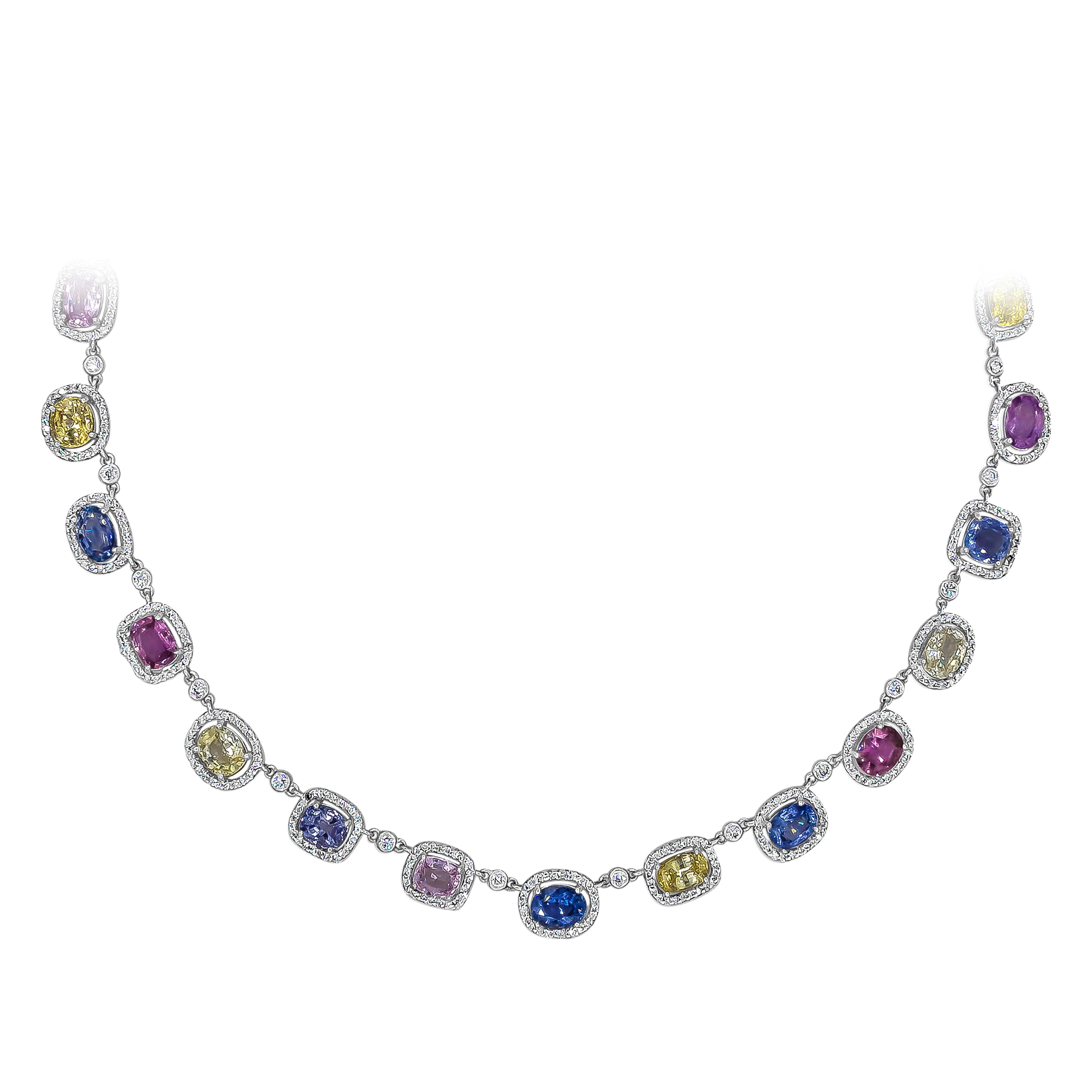 A brilliant jewelry piece showcasing a 37.41 carats total of multi color oval cut sapphires in a halo design and alternately spaced by brilliant round diamonds in a bezel set design. Diamonds weigh 5.55 carats total. Finely made in 18K White Gold
