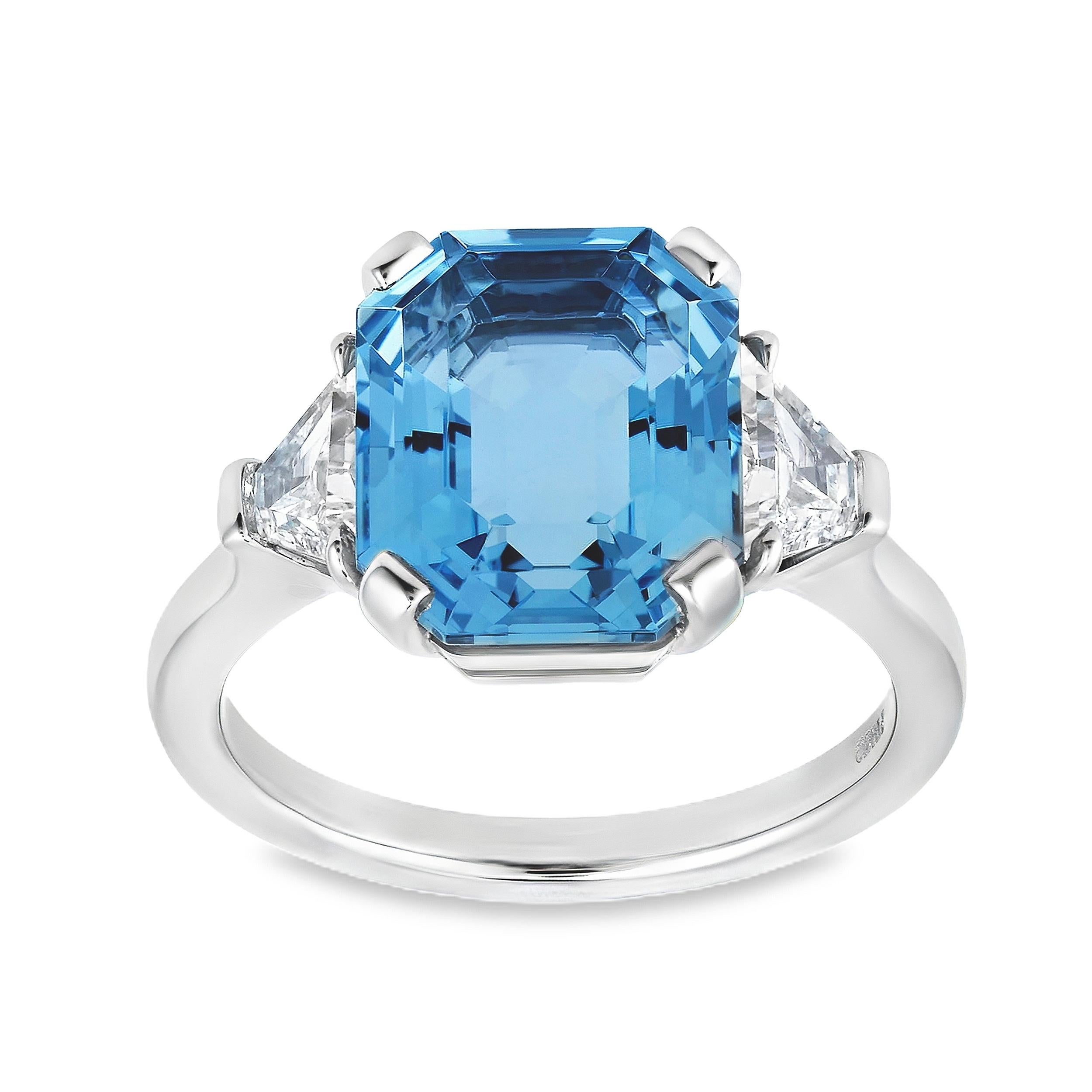 Ein wunderschöner Verlobungsring mit einem 3,84-karätigen Aquamarin im Smaragdschliff in einer klassischen Vier-Zacken-Fassung. Flankiert von zwei Diamanten im Trapezschliff mit einem Gesamtgewicht von 0.60 Karat. Fein gearbeitet mit einer