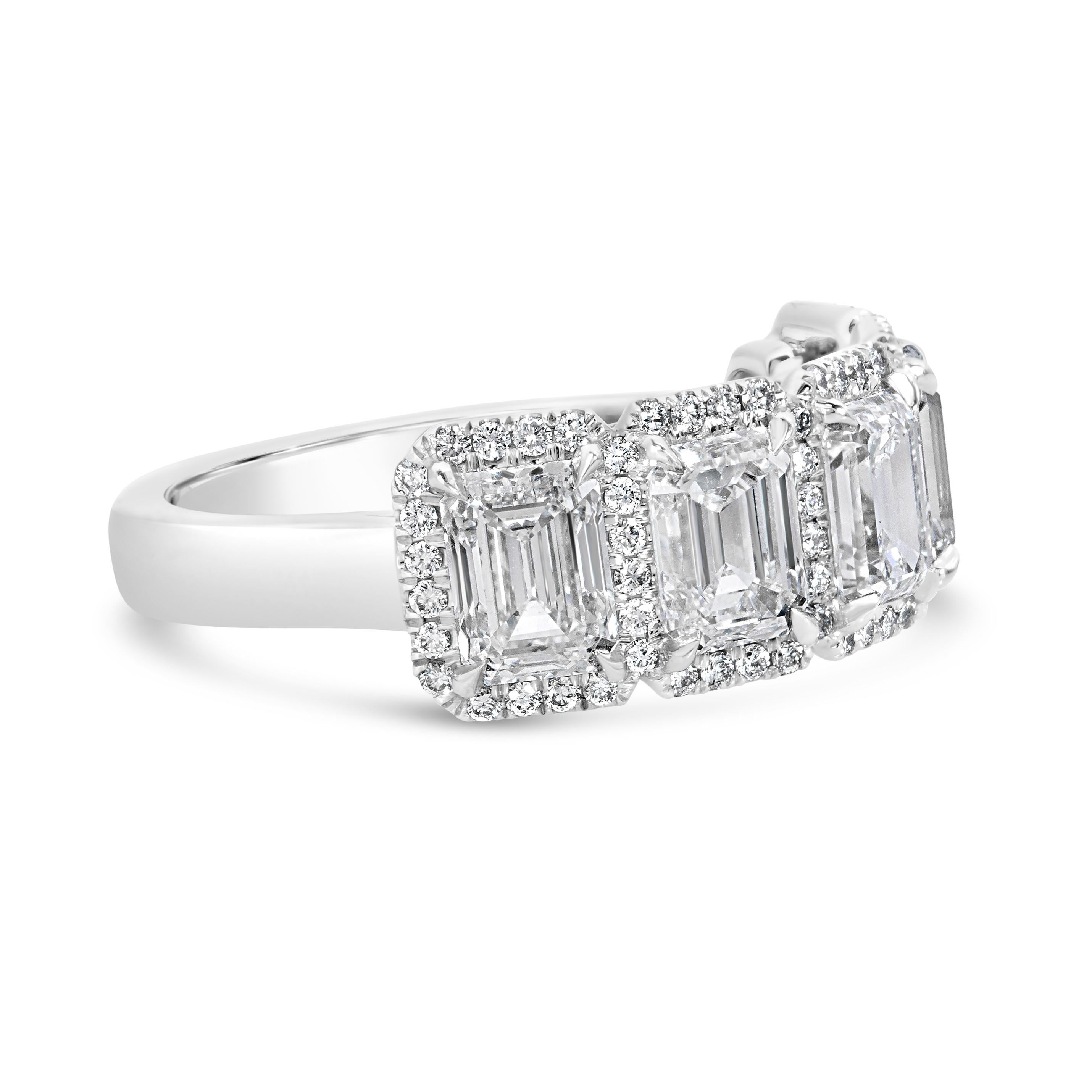 Ein wunderschöner Ehering mit fünf Diamanten im Smaragdschliff mit einem Gesamtgewicht von 3,62 Karat, die jeweils in einer vierzackigen Fassung gefasst sind. Akzentuiert durch einen gemeinsamen Halo aus runden Diamanten im Brillantschliff mit einem