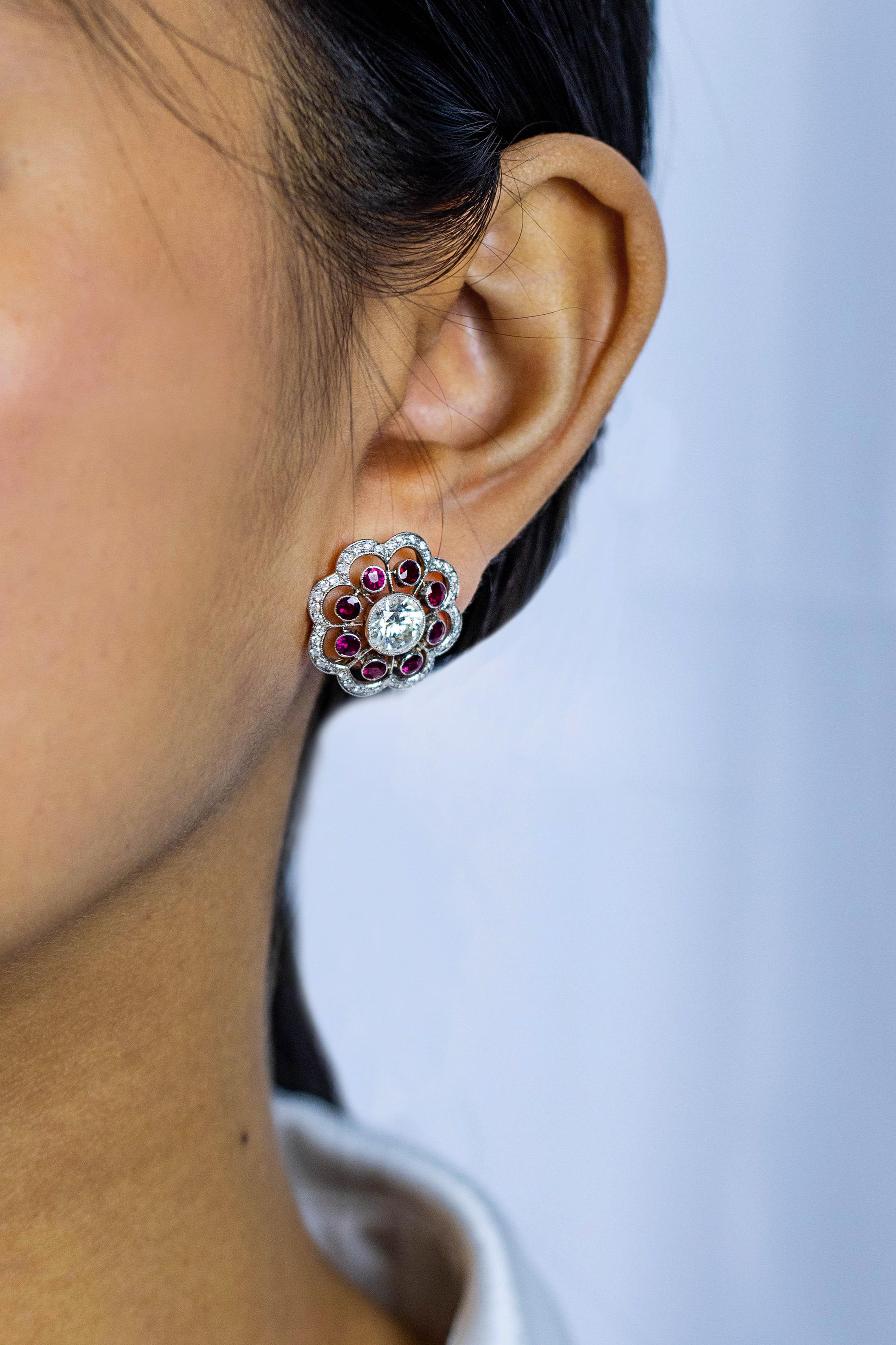 This gorgeous pair of stud earrings features brilliant round diamond center stone on each side which is approximately 2.50 carats in total, I color and VVS in clarity that embellished with 8 full-cut red rubies spaced evenly all around. Finished the