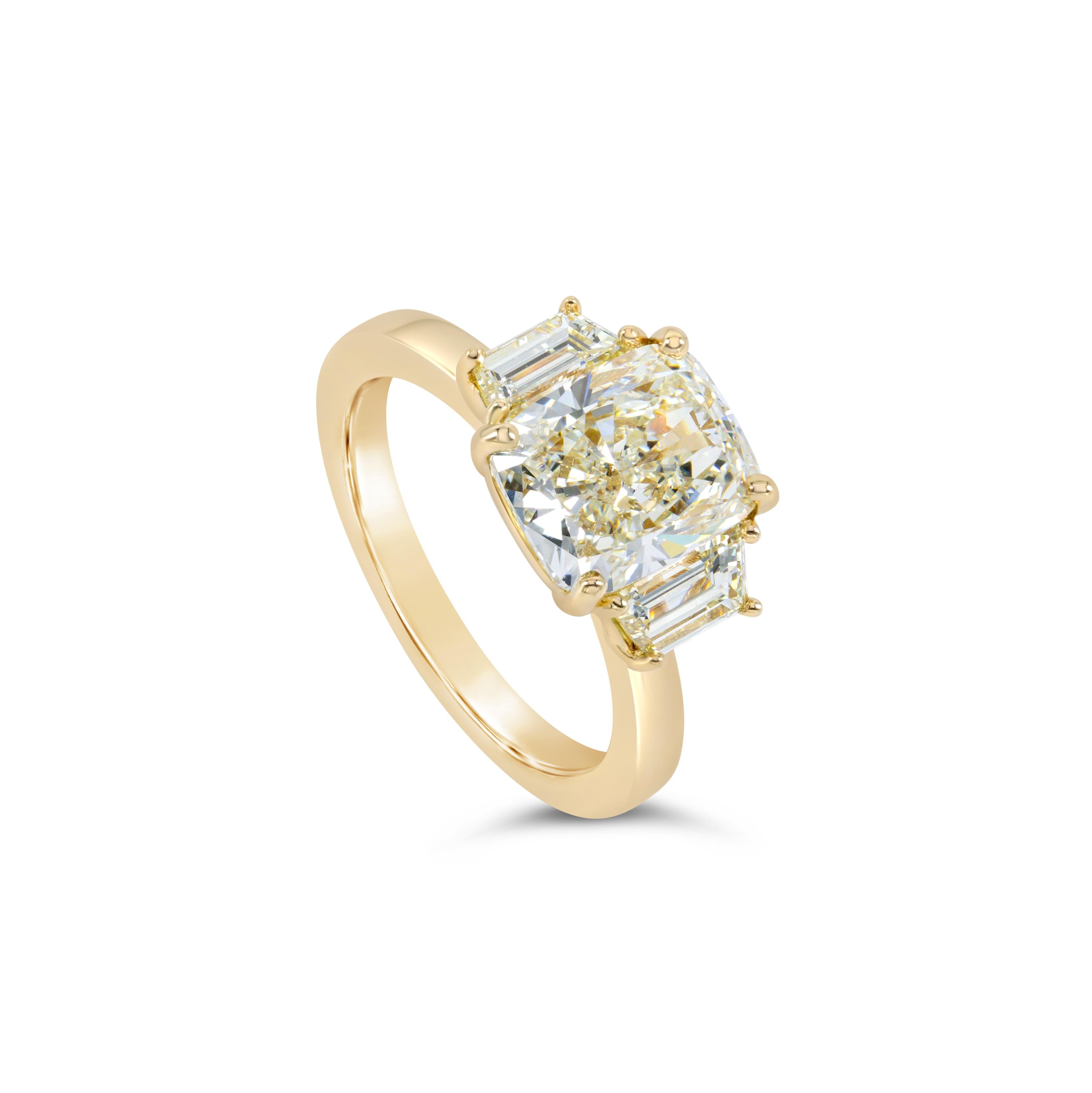 A gorgeous three-stone engagement ring, showcasing a 3.51 carats cushion cut diamond with M color and SI1 clarity. Accented by two tapered step-cut diamonds weighing 0.98 carat total. Each diamond is elegantly set on four rounded prongs. Finely made