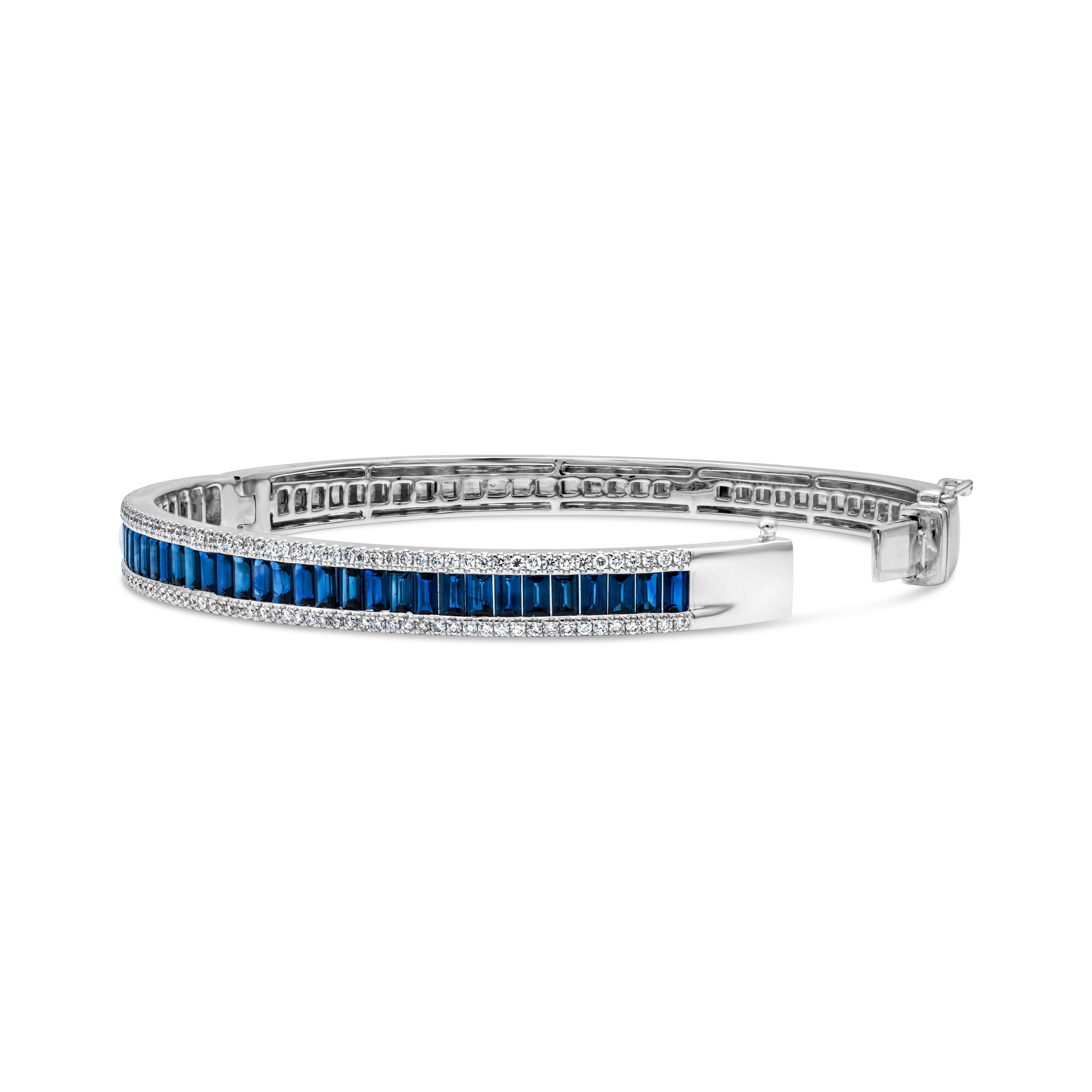 A brilliant & classic bangle bracelet showcasing a row of 34 baguette cut color-rich blue sapphires weighing 3.84 carats total, BS in clarity. Accented by 118 brilliant round cut diamonds weighing 0.71 carat total, G color and SI in clarity. Finely