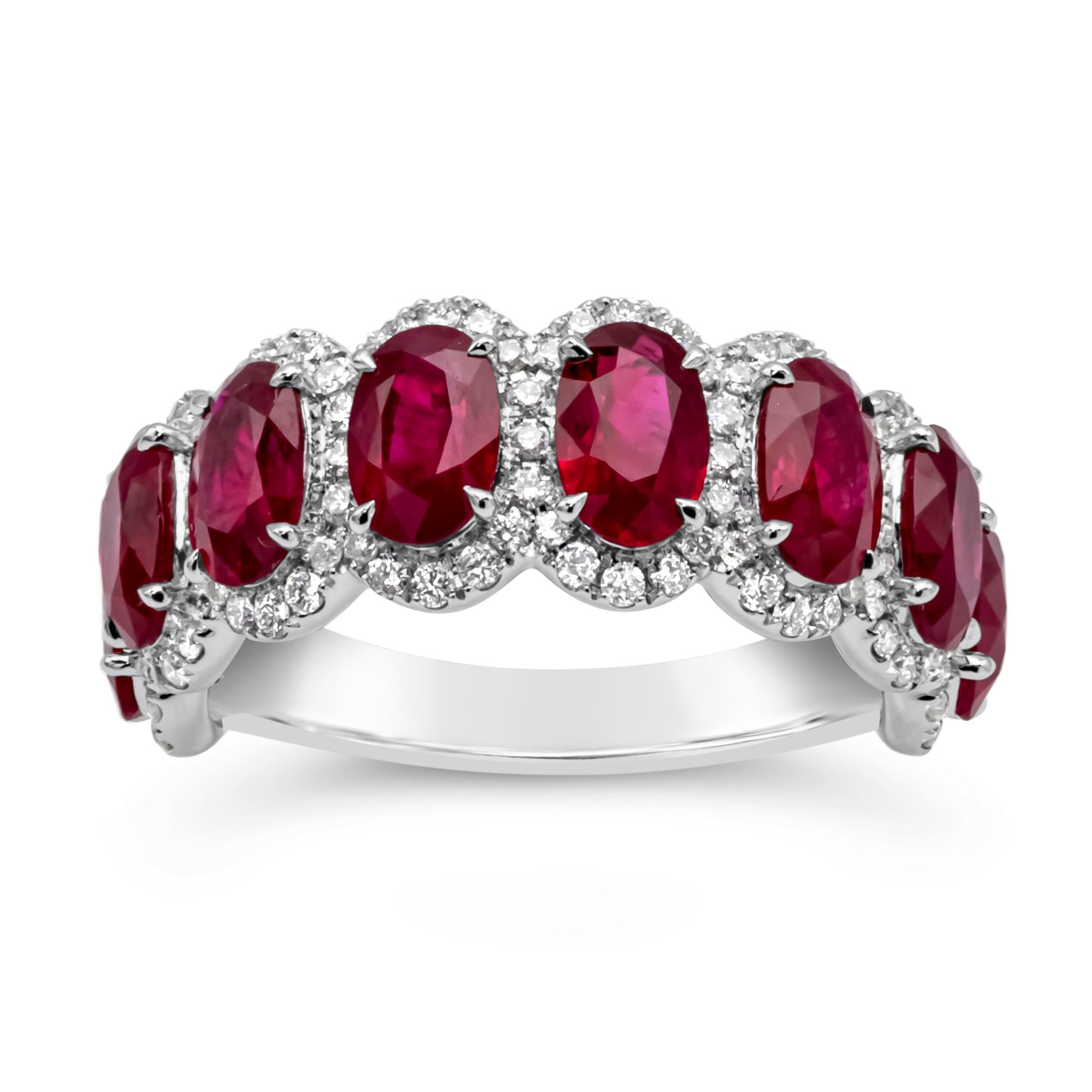 Cette fascinante alliance de pierres précieuses de style huit pierres présente une rangée de rubis ovales vibrants pesant 4,74 carats au total, entourés de diamants ronds brillants dans un design en halo pesant 0,55 carats, de couleur F et de pureté