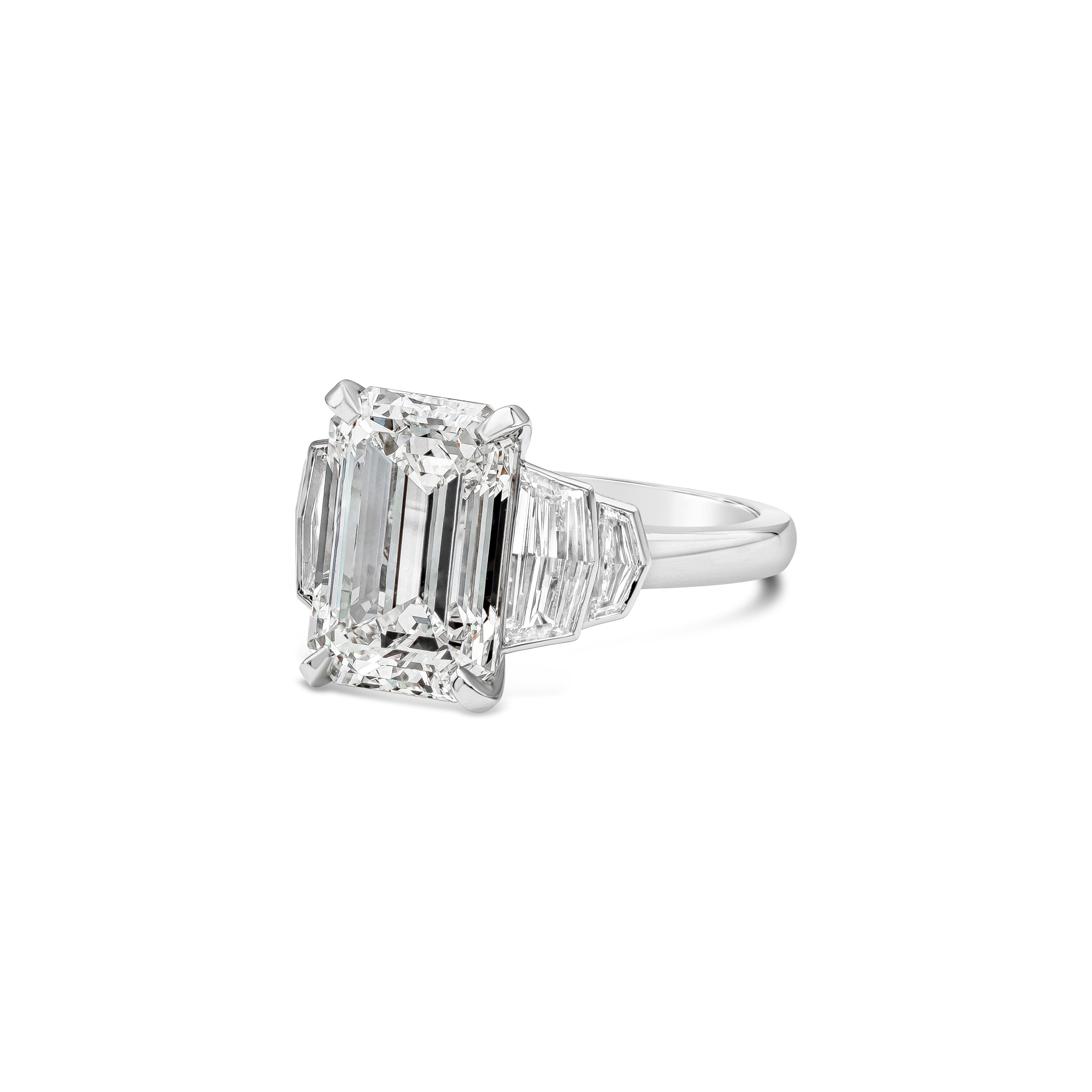 An elegant three-stone engagement ring, featuring a 5.01 carats emerald cut diamond certified by GIA as J color and SI2 clarity, set on a four prong setting. Flanked by step-cut epaulette diamonds weighing 0.88 carat total with H-I color and VS