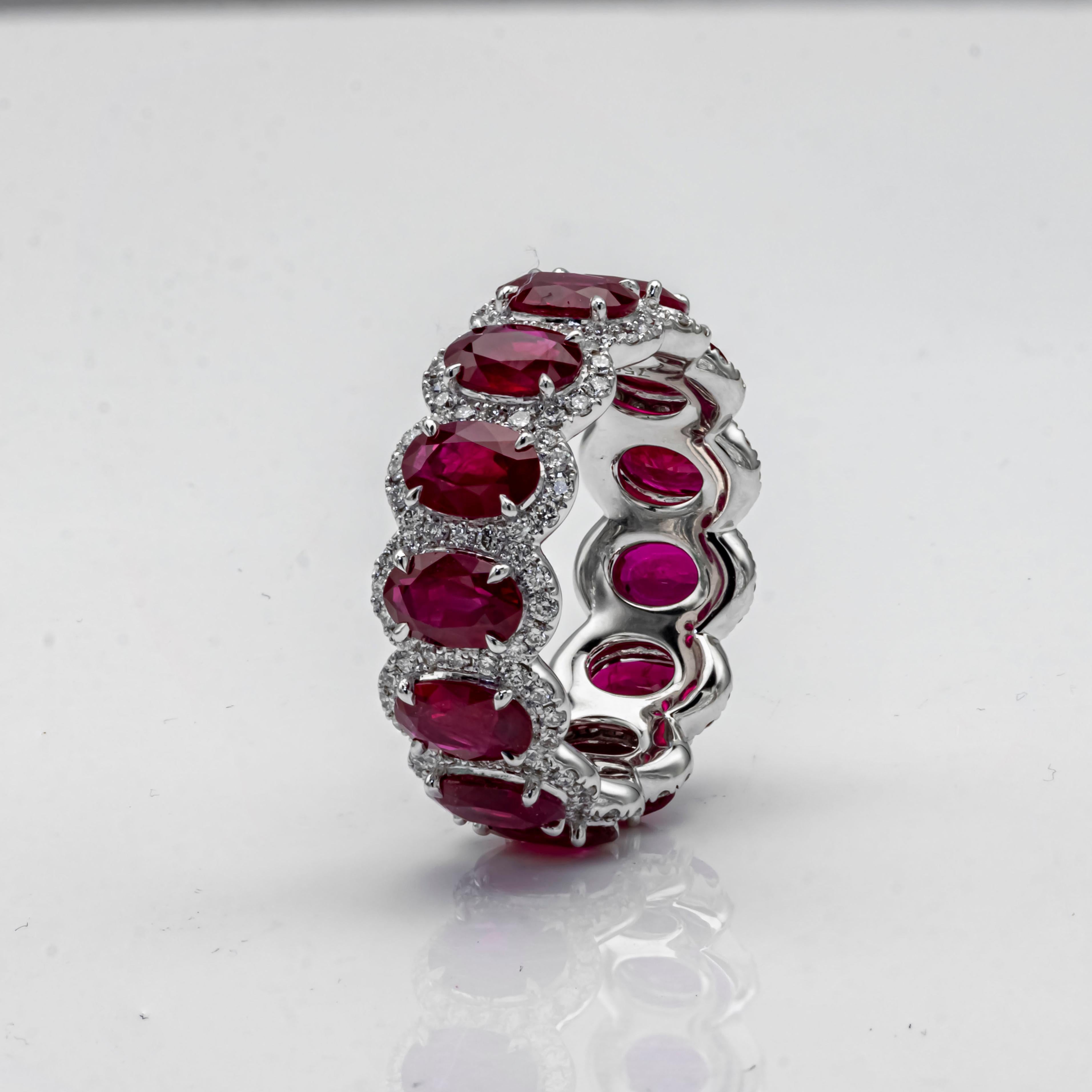 Elegantly crafted eternity wedding band ring showcasing thirteen oval cut red rubies weighing 6.38 carats total. Surrounded by 169 pieces row of round brilliant diamonds in halo setting. Diamonds weighs 0.85 carat total, G color and VS in clarity.