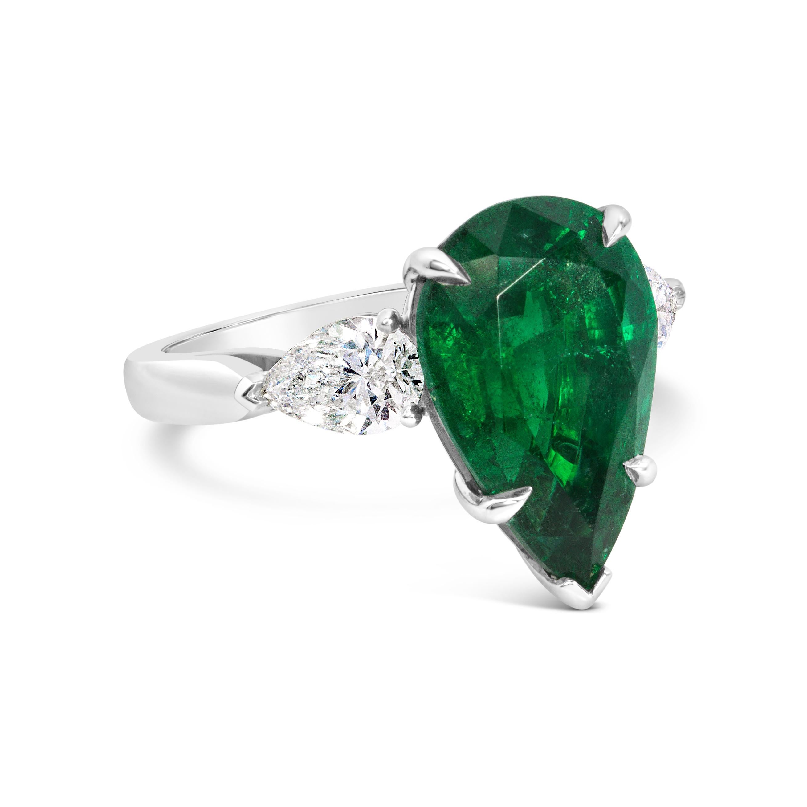 A beautiful cocktail ring, showcasing a 5.85 carats pear shape emerald certified by GIA as natural and of Zambian origin. Flanked by pear shape diamonds weighing 1.13 carats total. Finely made with a platinum mounting. Size 6 US, resizable upon