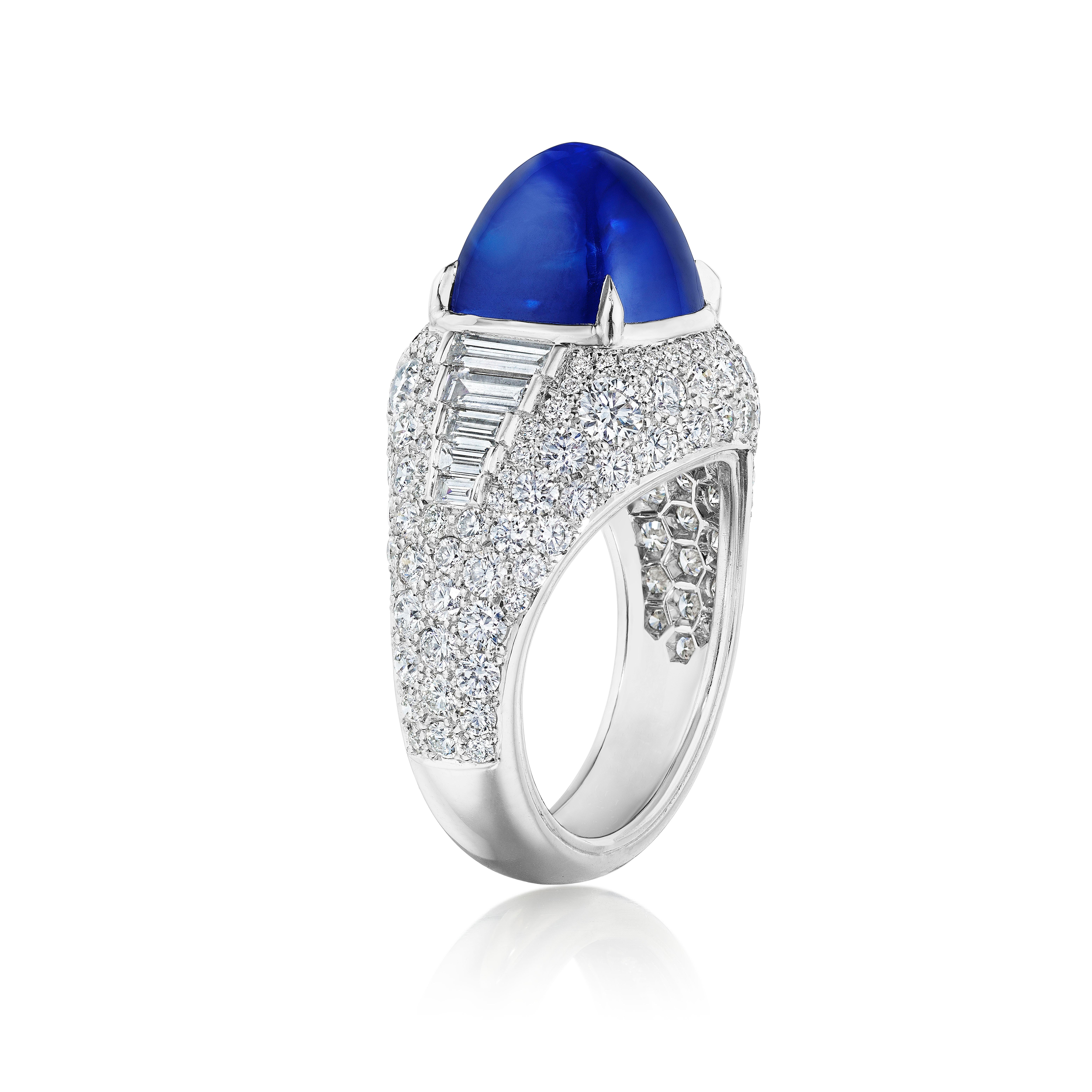 A stylish high-end cocktail ring, showcasing a 8.42 carats elongated blue cabochon flanked by 10 graduating baguette cut diamonds weighing 0.65 carat total and accented by 69 round cut diamonds weighing 2.03 carats total. All white diamonds have