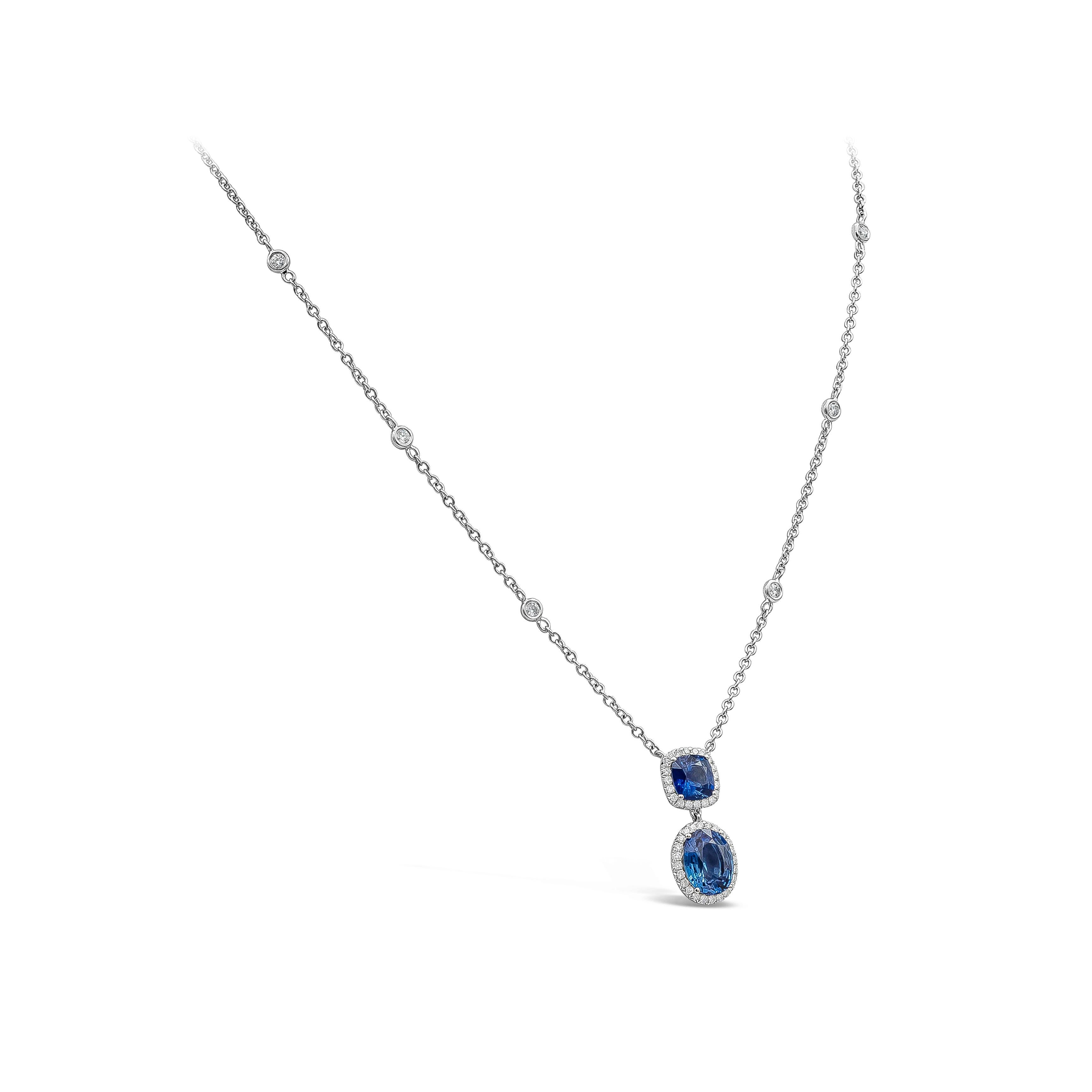 A simple and timeless pendant necklace showcasing an oval cut blue sapphire surrounded by a single row of round diamonds, suspended on a vibrant cushion cut blue sapphire and diamond halo. Attached to a diamonds by the yard chain made in 18K white